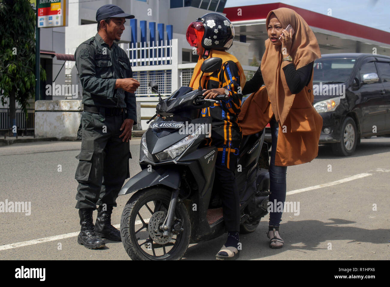 Die islamische Scharia Polizeioffizier (Wilayatul Hisbah) gesehen stoppen ein Kraftfahrer feste Kleidung tragen während des routinemäßigen Razzien in Lhokseumawe. Die islamische Scharia Polizisten (Wilayatul Hisbah) bieten sarongs Für diejenigen, die die islamische Scharia durch Gewalt in der Stadt Lhokseumawe verletzt, Aceh ist die einzige Provinz in Indonesien mit der größten Bevölkerung von Muslimen in der Welt, der die islamische Scharia wie Ausschuss caning implementiert und die Durchführung von routinemäßigen Raids Für diejenigen, die Fest für Frauen und kurze Hosen für Männer gekleidet sind. Stockfoto