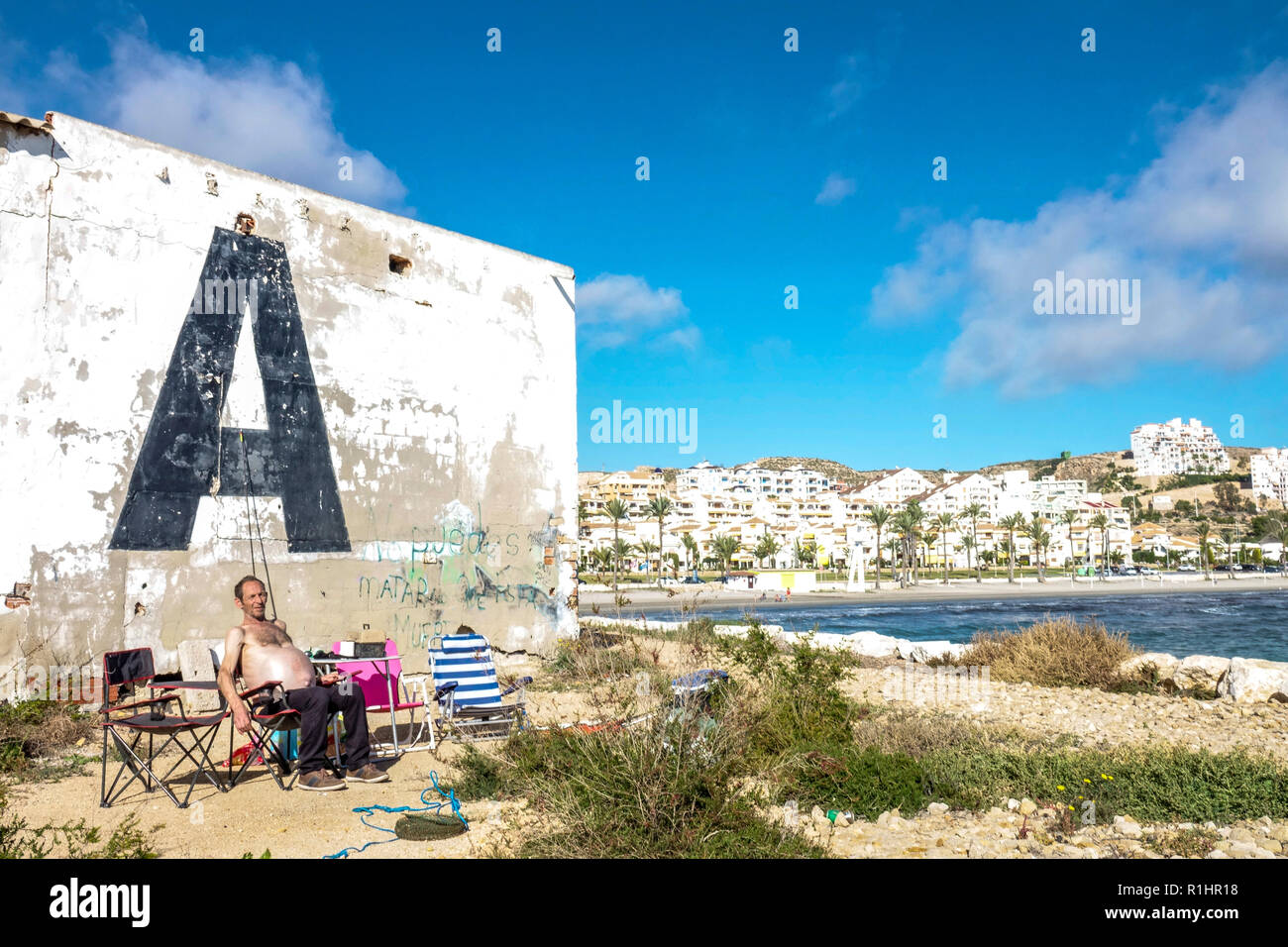 Strand in Santa Pola Spanien, ein entspannender Senior Fischer am Pier im November, Wandbild großer Brief Ein riesiger Senior Erwachsener Stockfoto