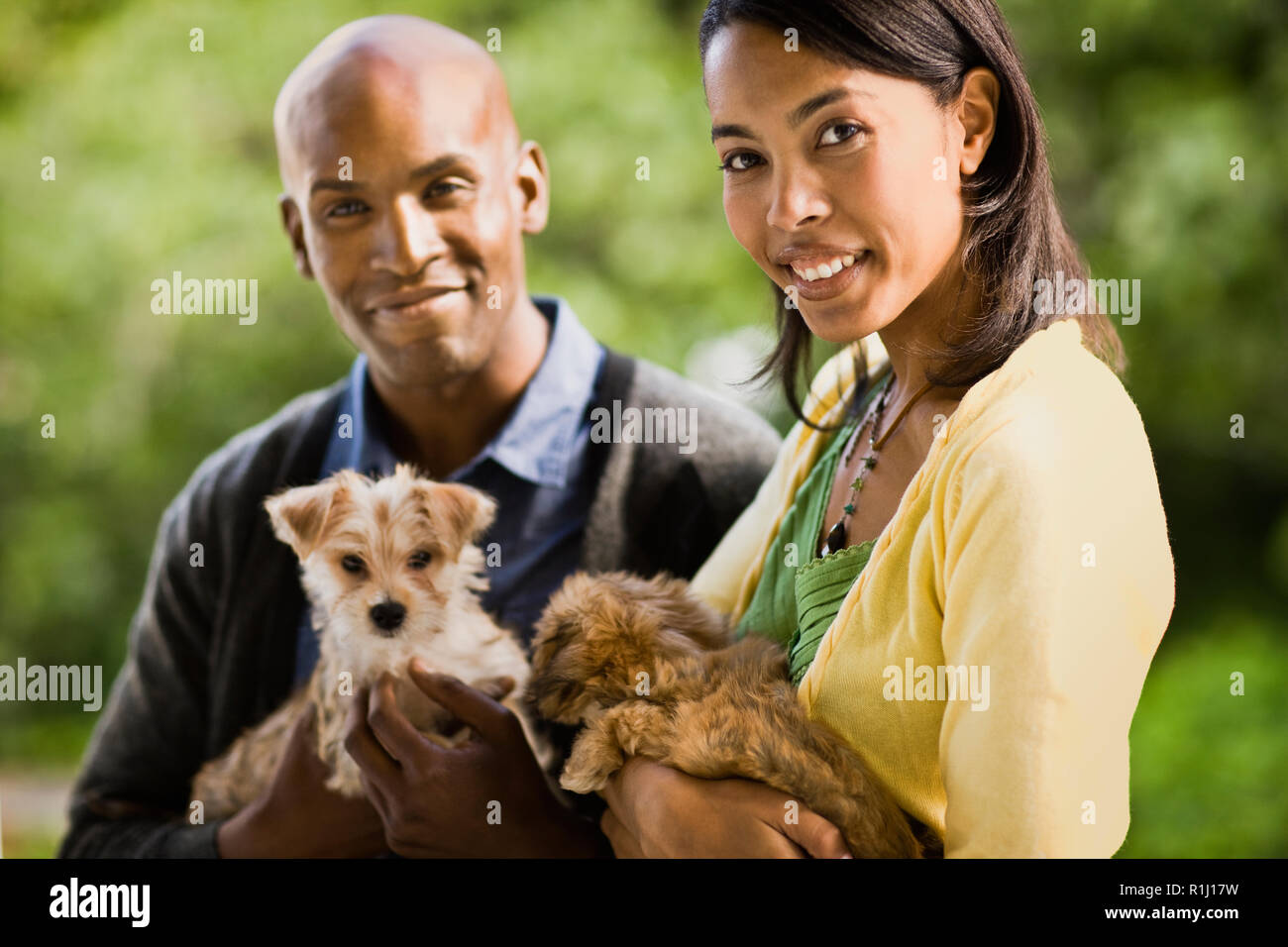 Junge heterosexuellen Paaren, Lächeln, als sie Welpen halten und für ein Portrait darstellen. Stockfoto