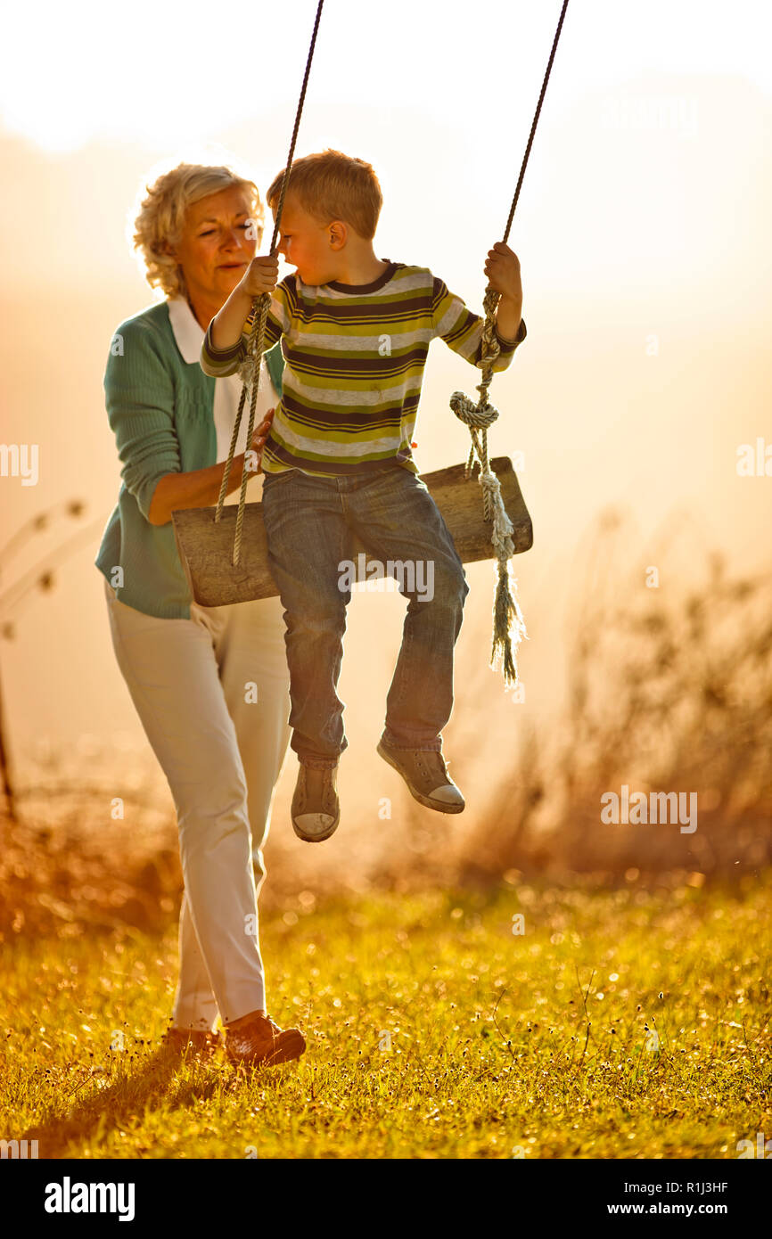 Little Boy spielen auf dem Baum schwingen mit seiner Großmutter. Stockfoto