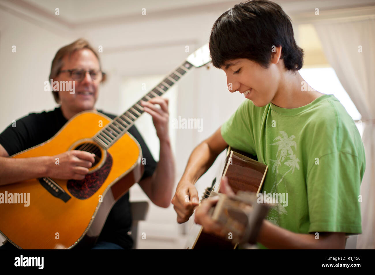 Teenager und reifer Mann spielt akustische Gitarren. Stockfoto