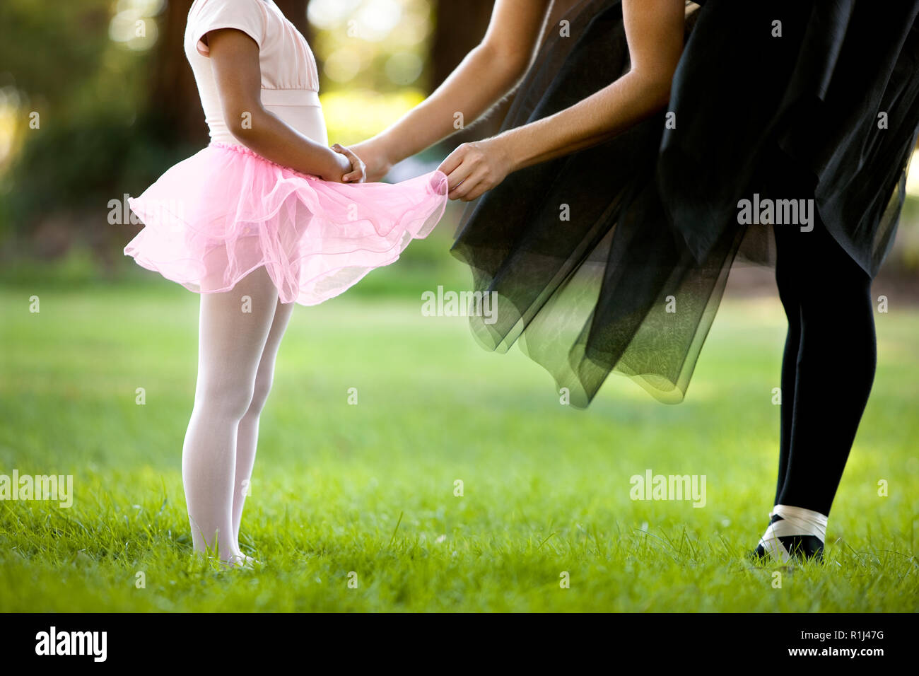Mitte der erwachsenen Frau und ihre junge Tochter Ballett tanzen in einen Park. Stockfoto