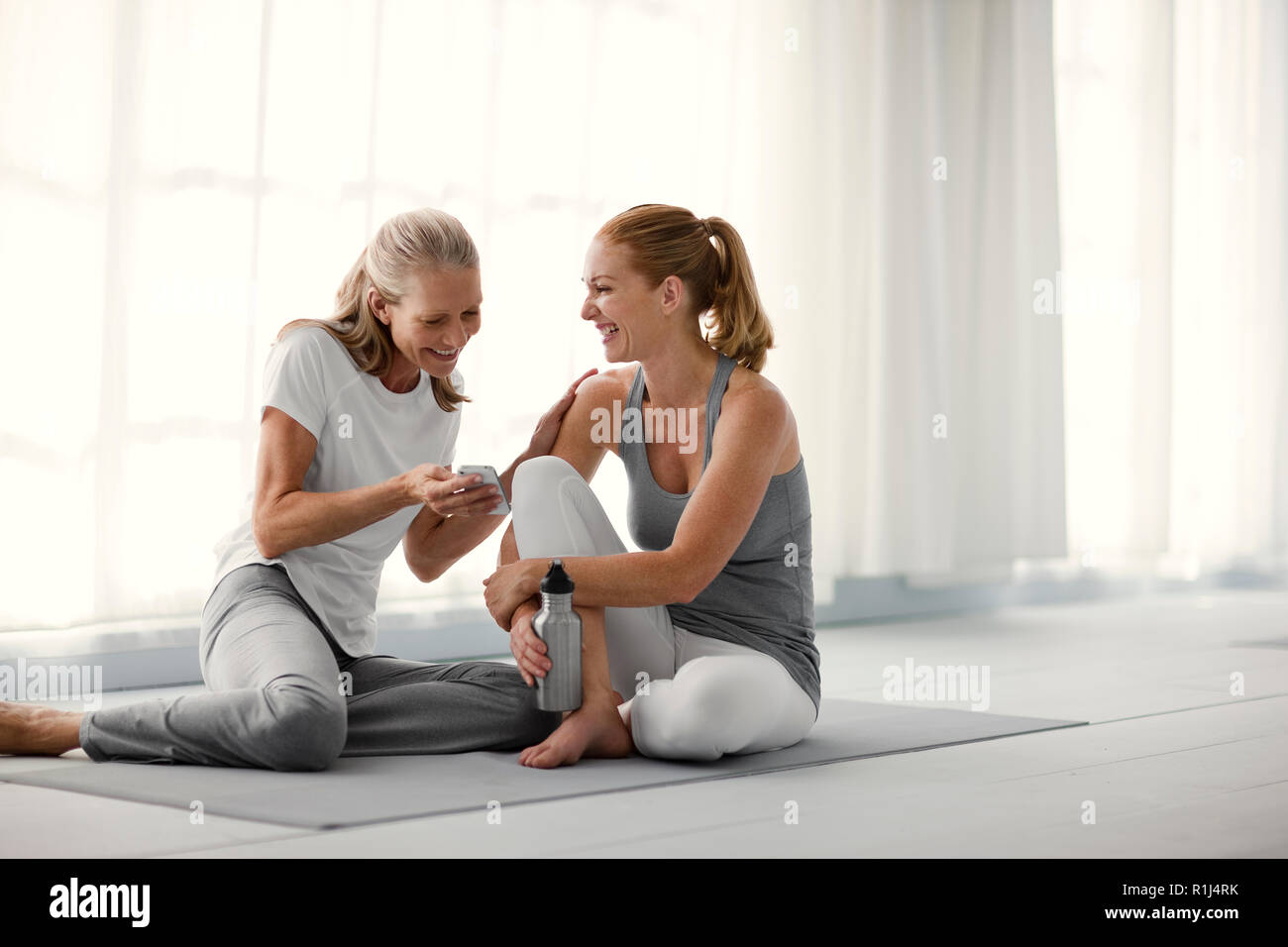 Lächelnd, reife Frau zeigt ihre Freundin etwas auf Ihr Smartphone. Stockfoto