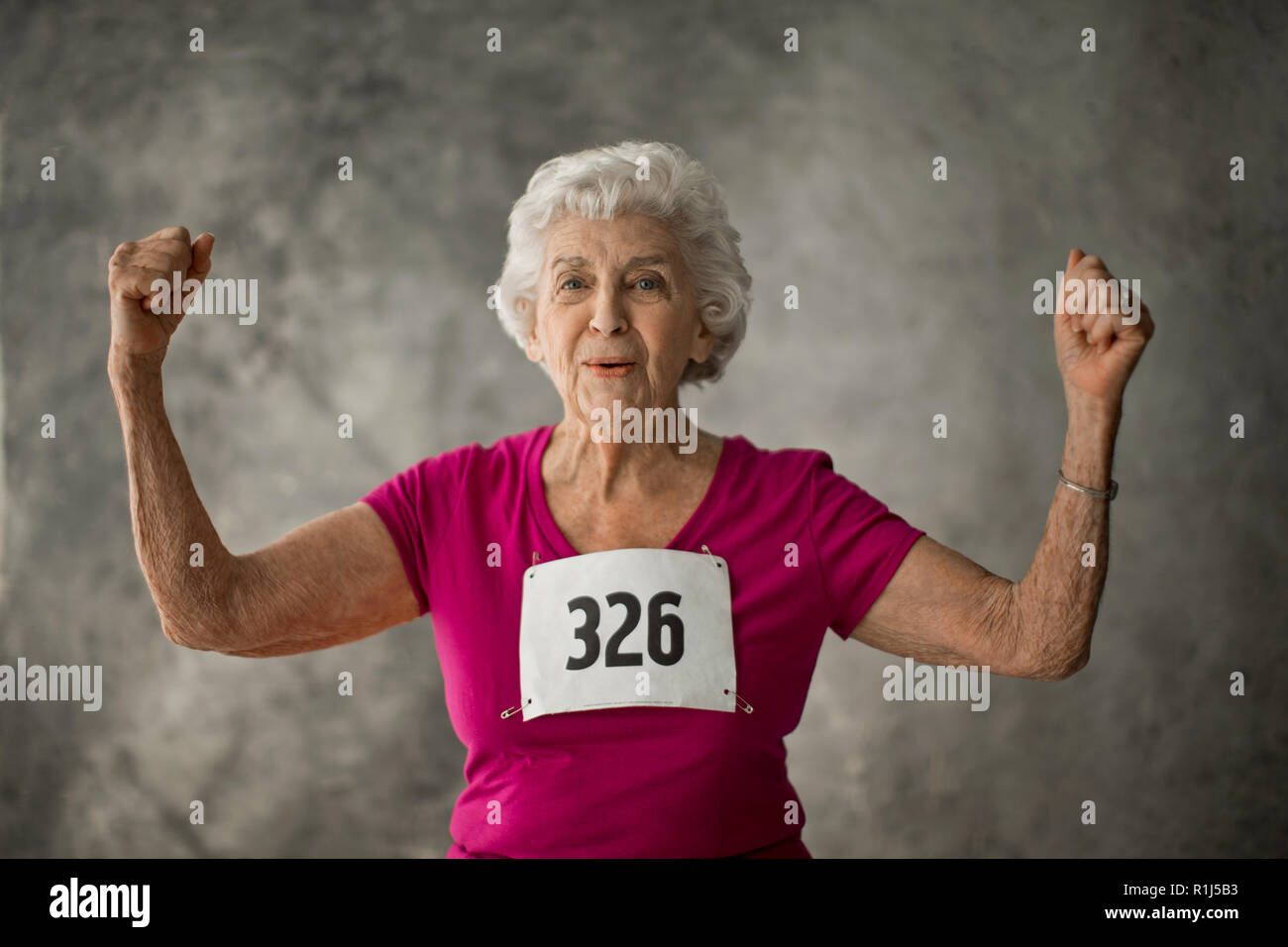 Porträt einer gerne ältere Frau aus ihrer Armmuskulatur. Stockfoto