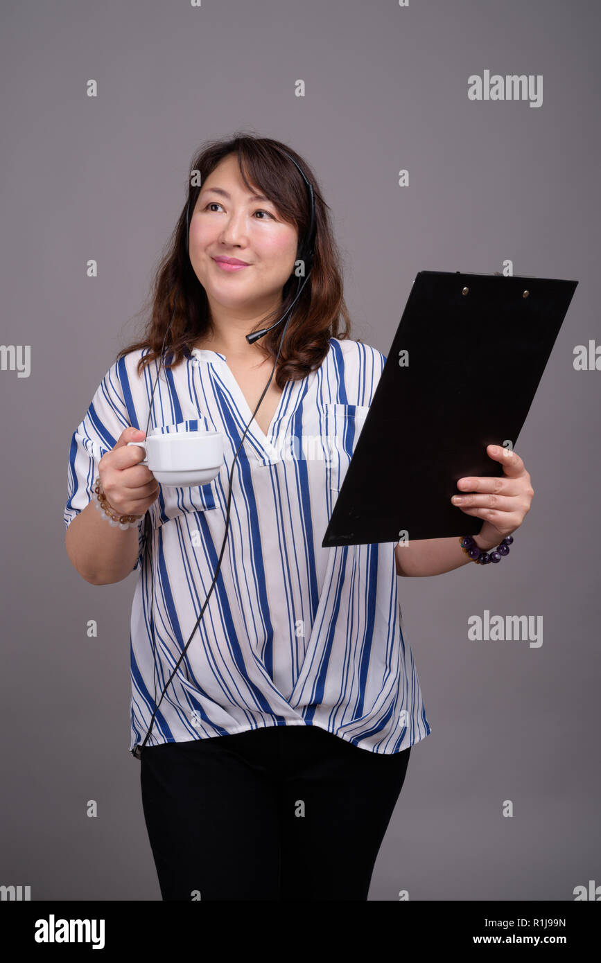 Reifen schöne asiatische Geschäftsfrau gegen grauer Hintergrund Stockfoto