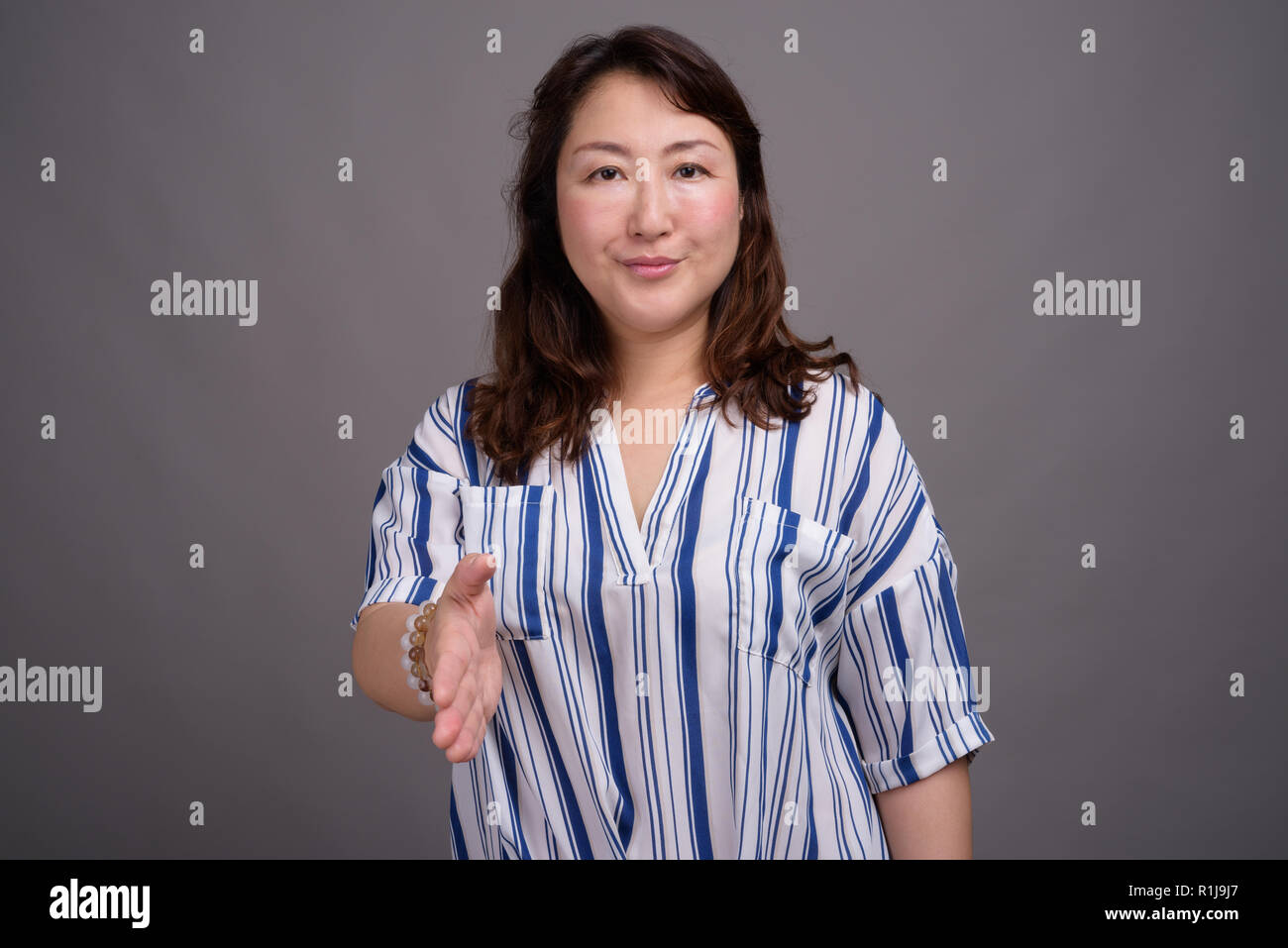 Reifen schöne asiatische Geschäftsfrau gegen grauer Hintergrund Stockfoto