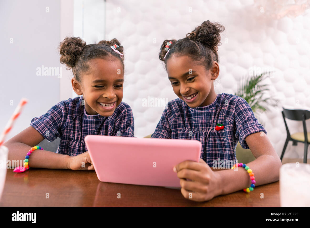 Zwei strahlende Lachen Geschwister cartoon Beobachten auf ihre rosa Tablette Stockfoto