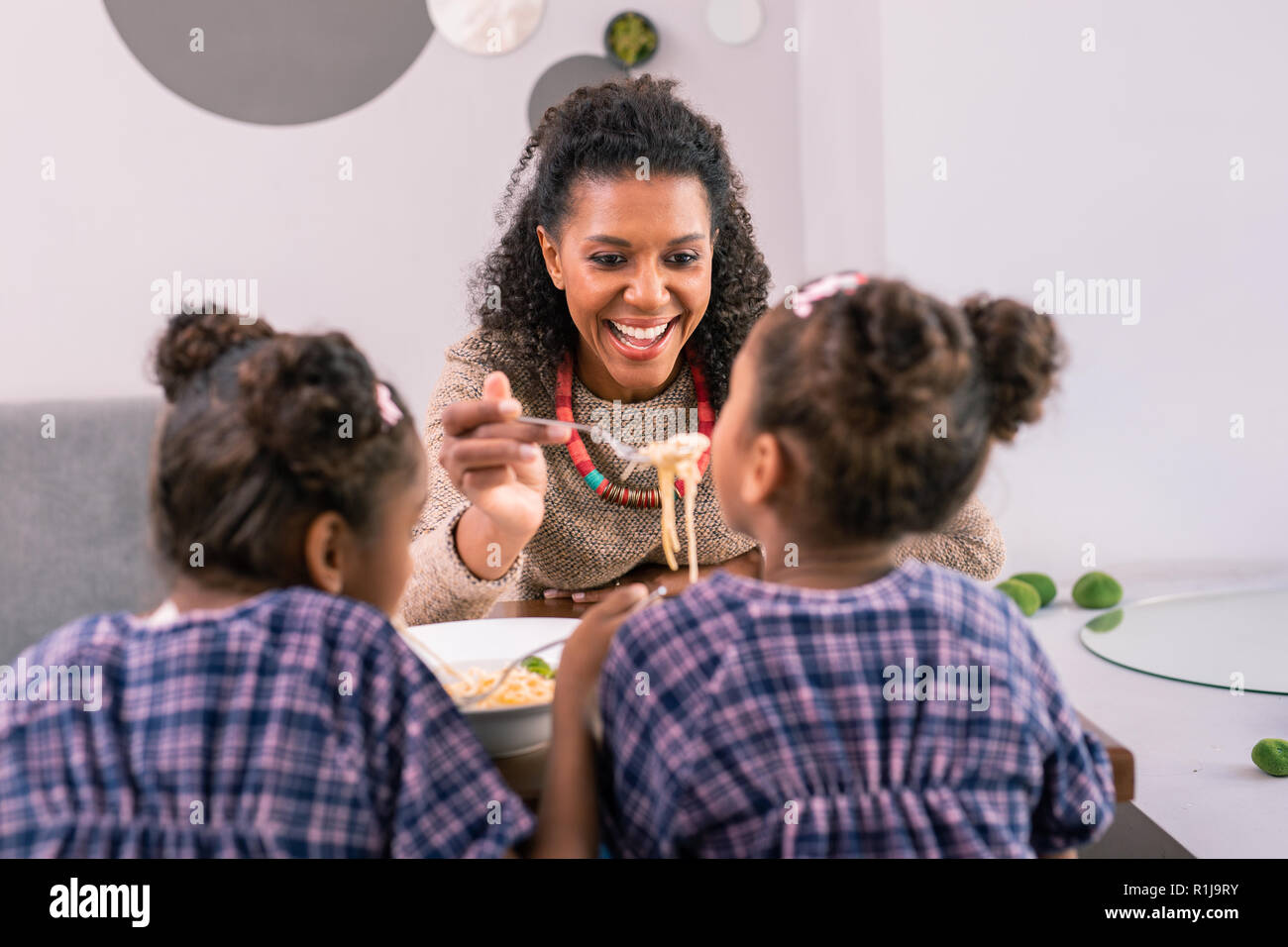 Übertragen von Curly dark-eyed Mutter kümmert sich um Ihr süßes Mädchen in der Cafeteria Stockfoto