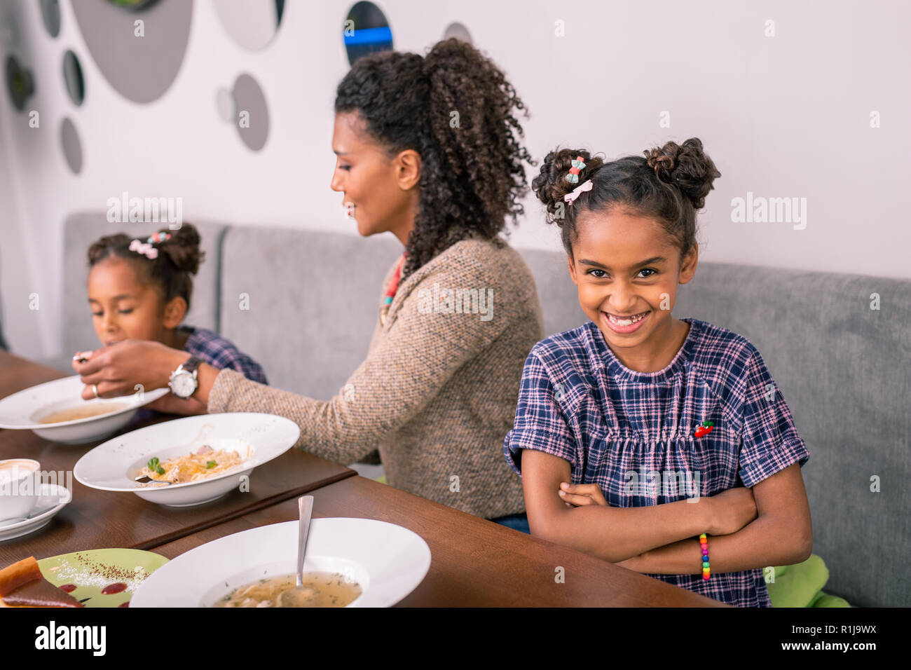 Cute dark-eyed Tochter Gefühl fröhlichen beim Genießen Familie Mittagessen Stockfoto