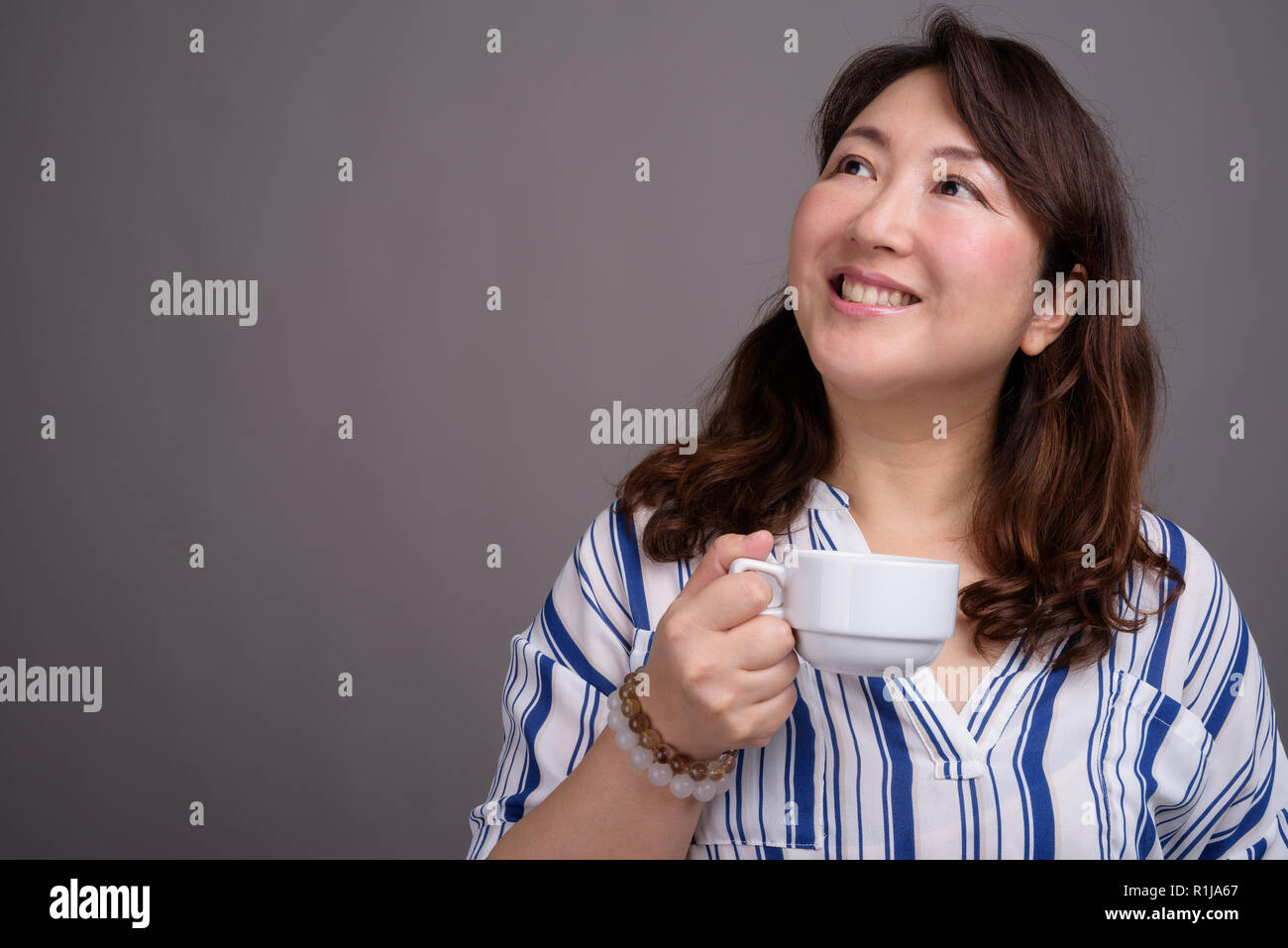 Reifen schöne asiatische Geschäftsfrau holding Kaffeetasse Stockfoto
