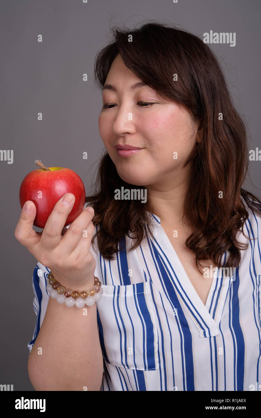 Reifen schöne asiatische Geschäftsfrau hält gesund Apple Stockfoto