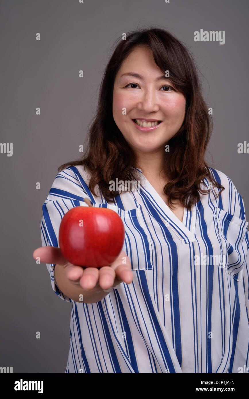 Reifen schöne asiatische Geschäftsfrau hält gesund Apple Stockfoto