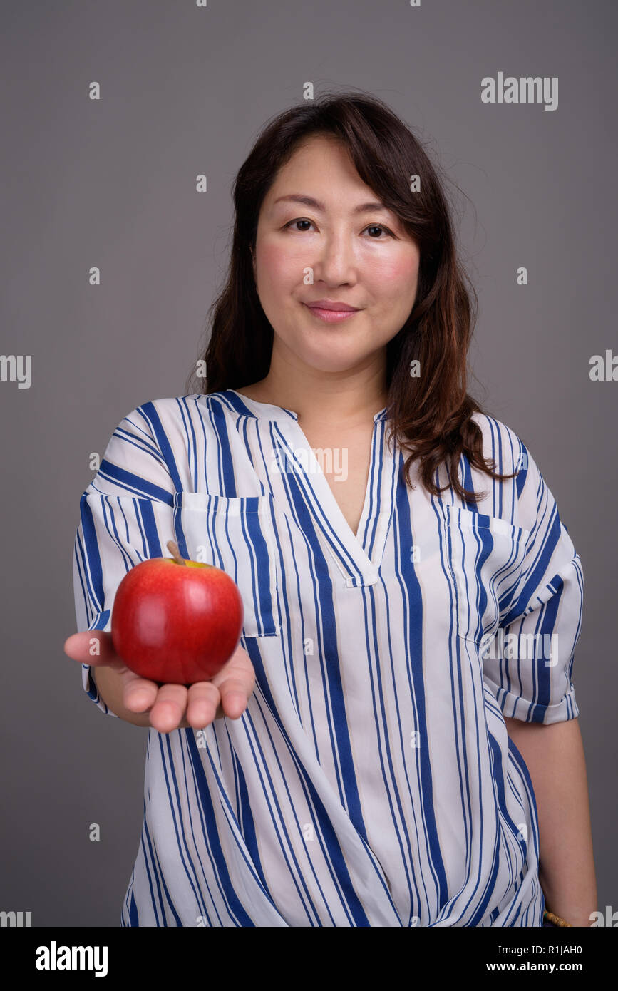 Reifen schöne asiatische Geschäftsfrau hält gesund Apple Stockfoto