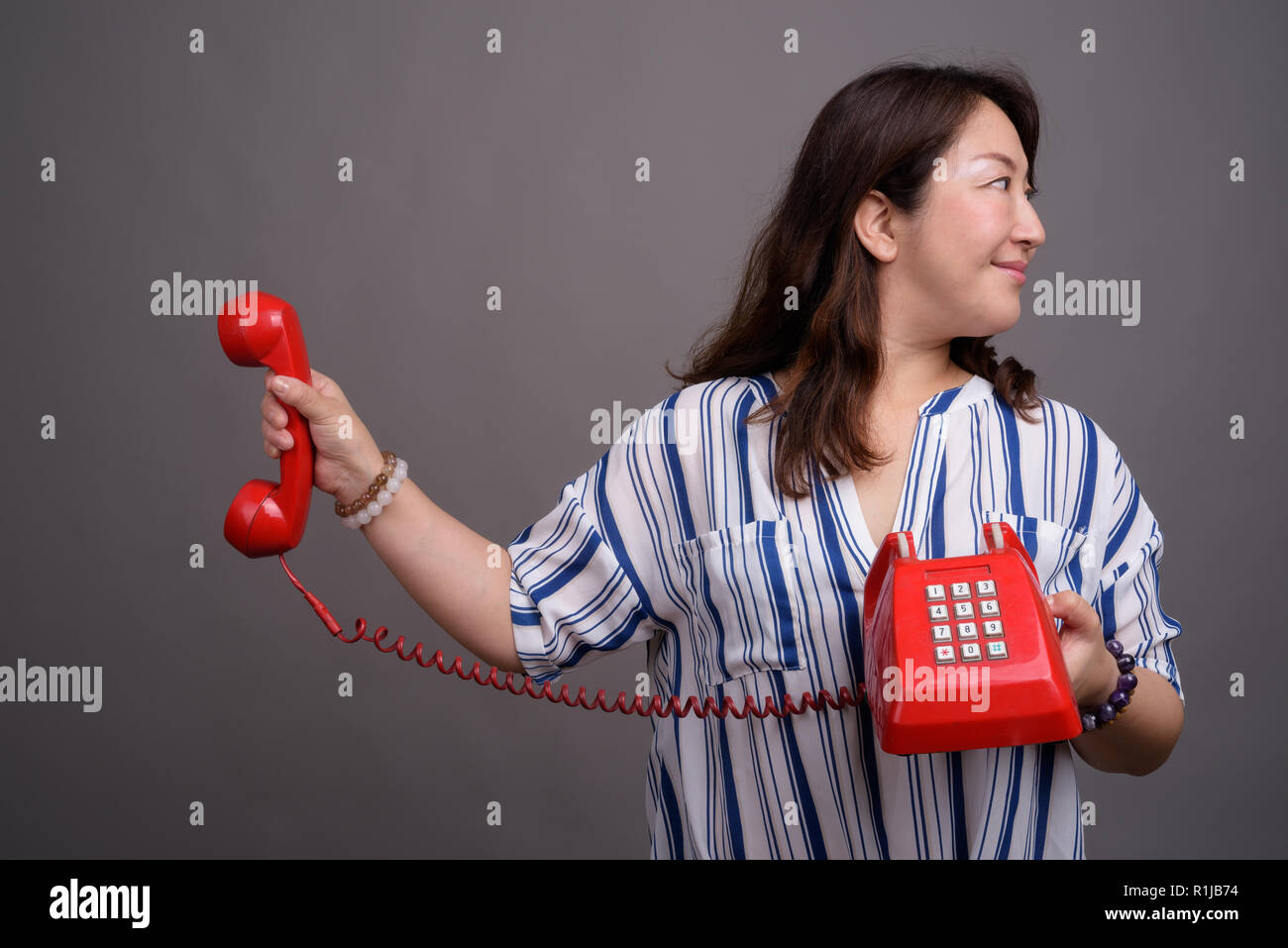 Reifen schöne asiatische Geschäftsfrau Holding alten roten Telefon Stockfoto