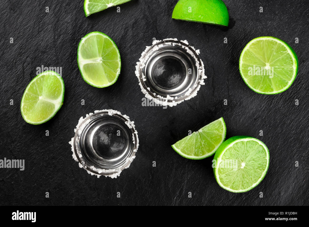 Zwei tequila Schüsse mit vielen Kalk Scheiben, geschossen von oben auf einen dunklen Hintergrund Stockfoto