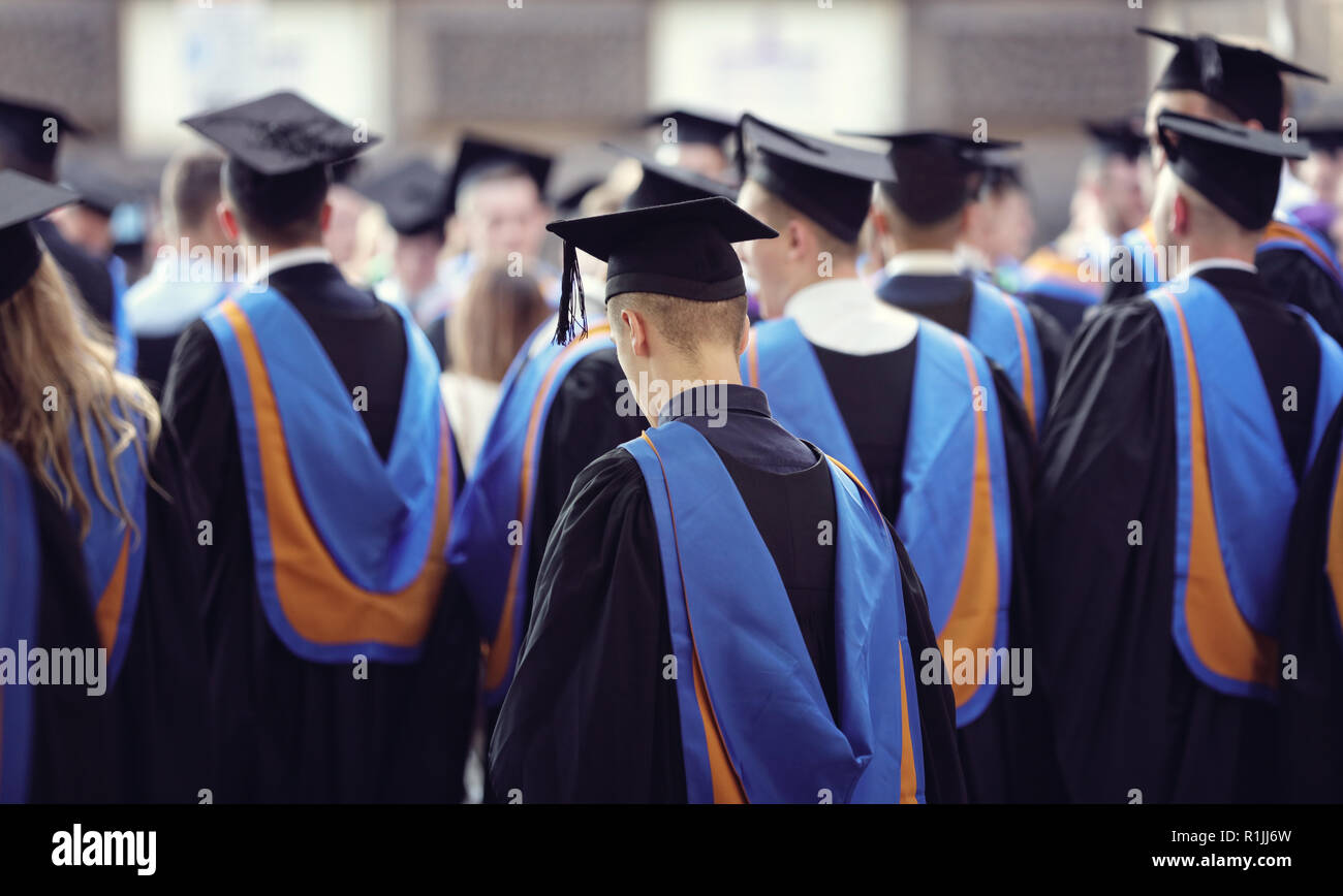 Die Absolventen an der Universität Abschlussfeier tragen mortarboard und Kleid Stockfoto