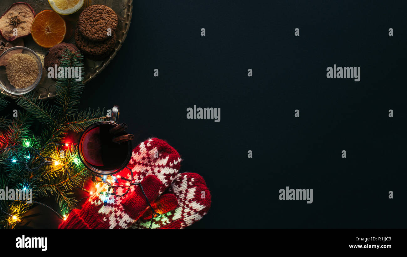 Ansicht von Glühwein, Garland, Fäustlinge und Cookies auf schwarz, Weihnachten Konzept isoliert Stockfoto