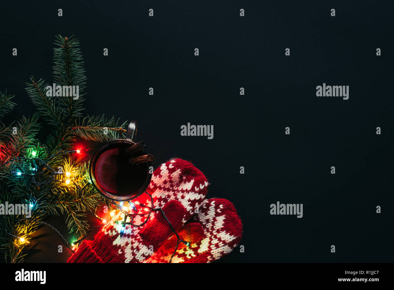 Blick von oben auf die Tasse Glühwein, Girlanden und Handschuhe auf schwarz, Weihnachten Konzept isoliert Stockfoto