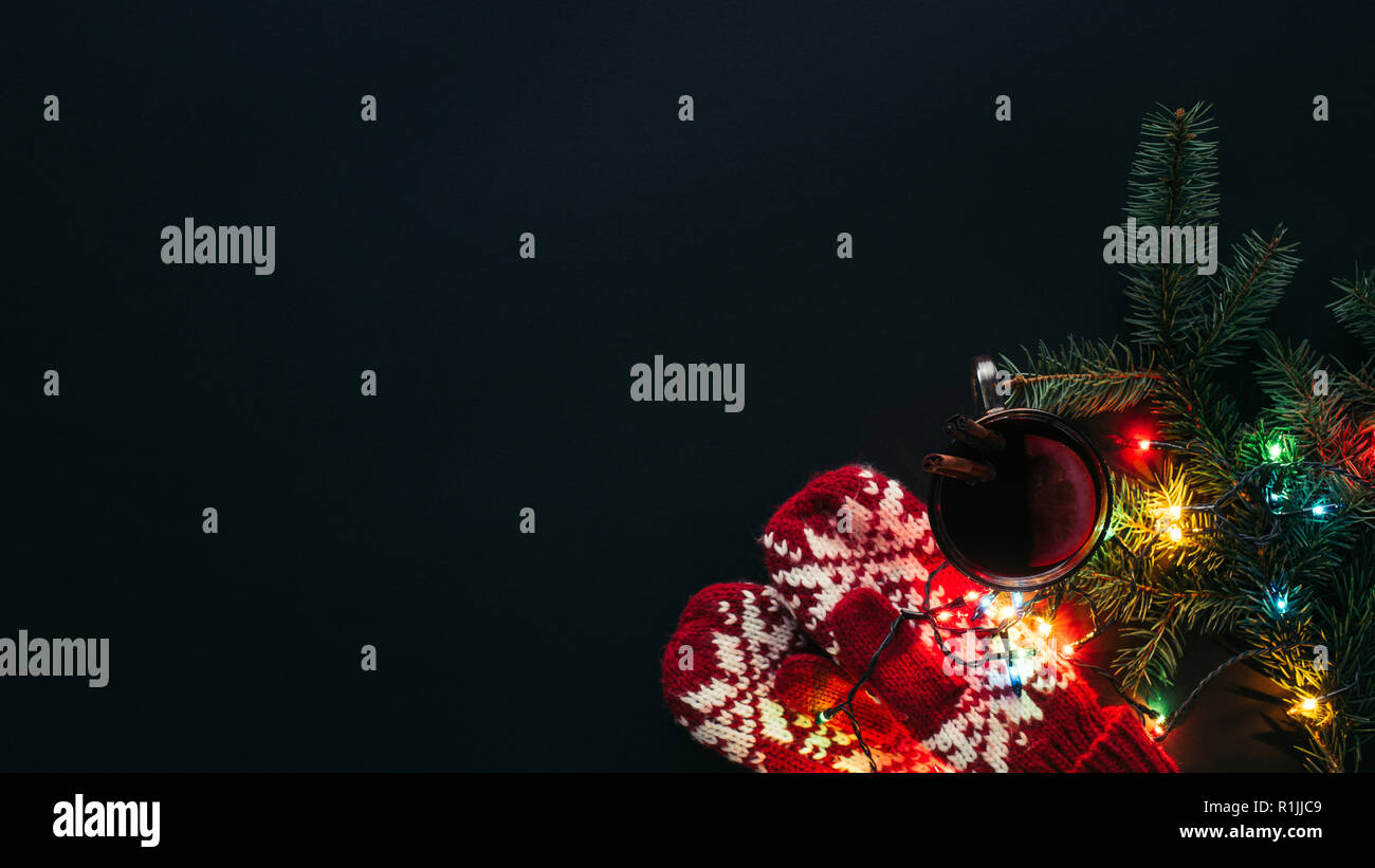 Ansicht der Tasse Glühwein, Girlanden und Handschuhe auf schwarz, Weihnachten Konzept isoliert Stockfoto