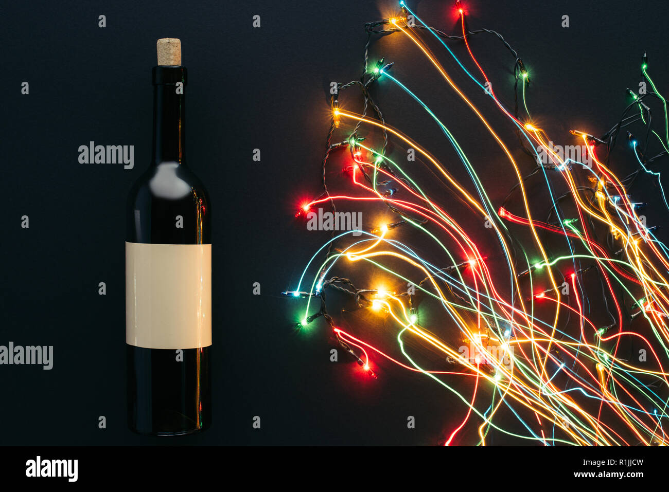 Ansicht von Wein Flasche und girlande Lichter mit langen Belichtung auf schwarz, Weihnachten Konzept isoliert Stockfoto