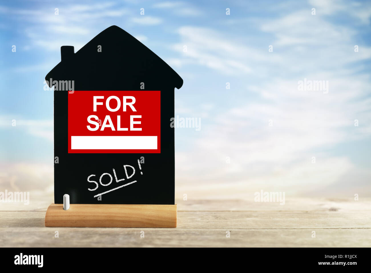 Immobilienmakler für Verkauf Zeichen mit auf Haus Form Kreide Tafel verkauft Stockfoto