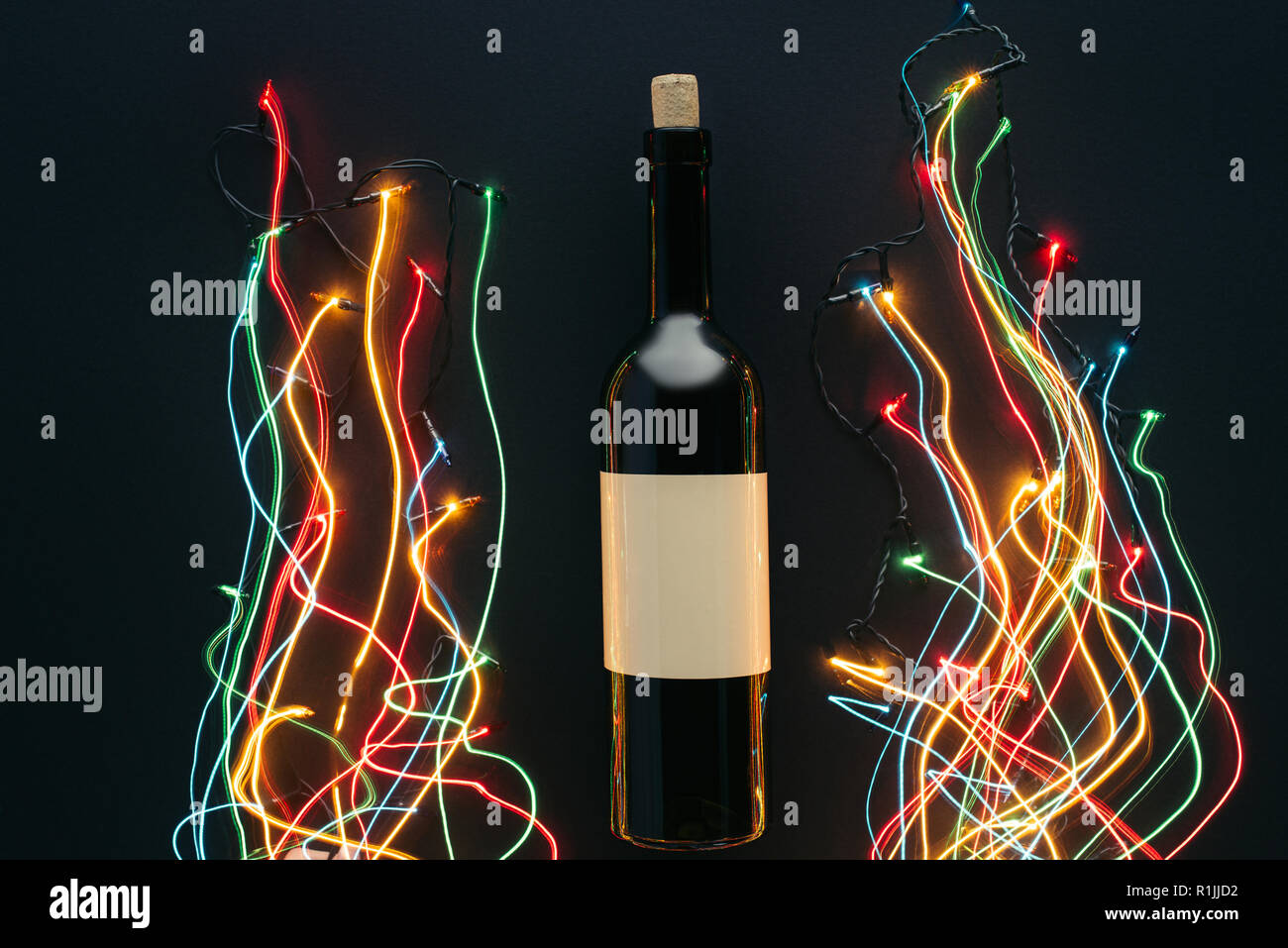 Blick von oben auf die Flasche Wein und girlande Lichter mit langen Belichtung auf schwarz, Weihnachten Konzept isoliert Stockfoto