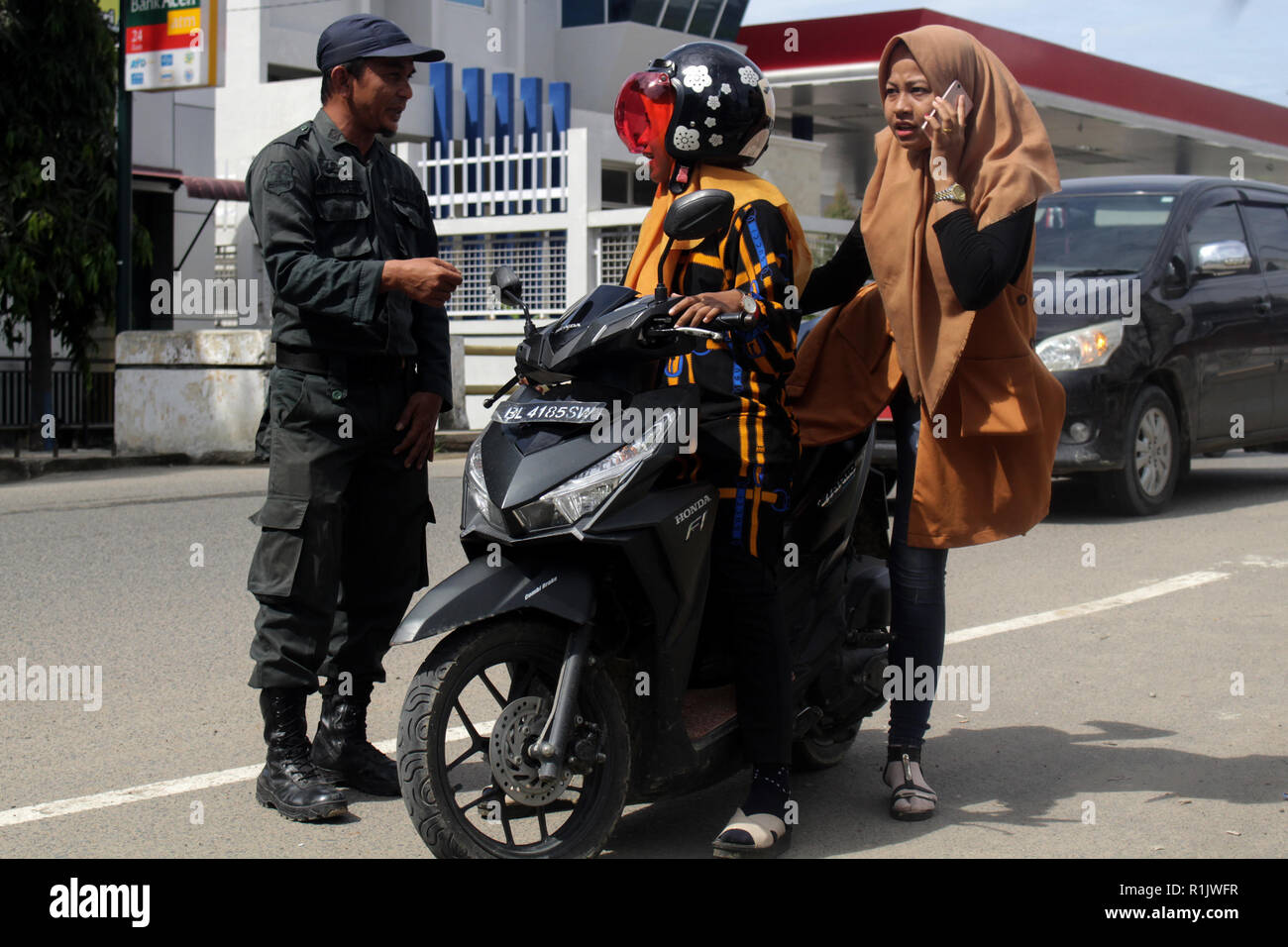 Lhokseumawe, Aceh, Indonesien. 13 Nov, 2018. Die islamische Scharia Polizeioffizier (Wilayatul Hisbah) gesehen stoppen ein Kraftfahrer feste Kleidung tragen während des routinemäßigen Razzien in Lhokseumawe. islamische Scharia Polizisten (Wilayatul Hisbah) bieten sarongs Für diejenigen, die die islamische Scharia durch Gewalt in der Stadt Lhokseumawe verletzt, Aceh ist die einzige Provinz in Indonesien mit der größten Bevölkerung von Muslimen in der Welt, der die islamische Scharia wie Ausschuss caning implementiert und die Durchführung von routinemäßigen Raids Für diejenigen, die Fest für Frauen und kurze Hosen für Männer gekleidet sind. (Cre Stockfoto