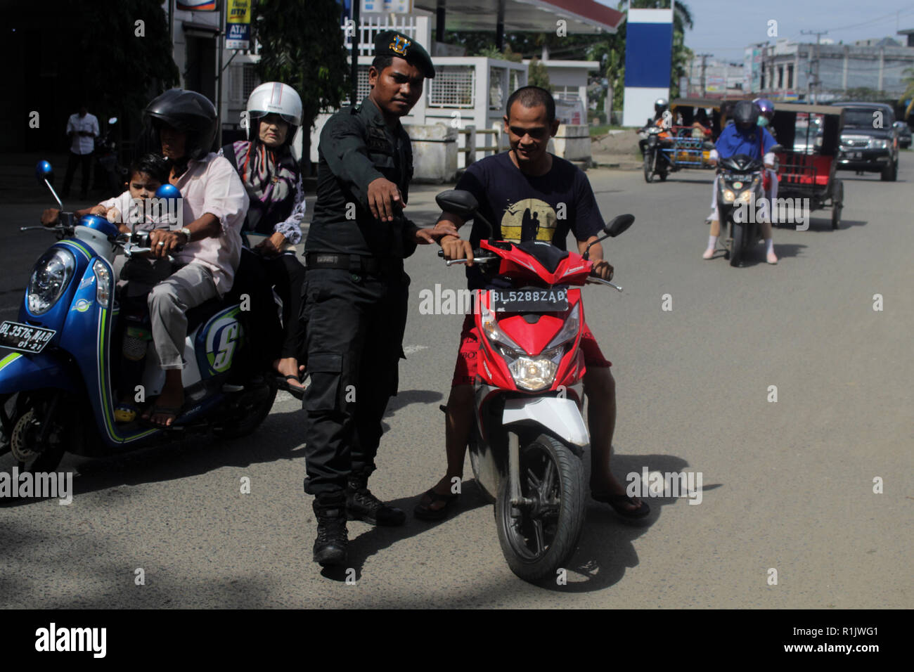 Lhokseumawe, Aceh, Indonesien. 13 Nov, 2018. Die islamische Scharia Polizeioffizier (Wilayatul Hisbah) gesehen stoppen ein Kraftfahrer einen Kurzschluß tragen während des routinemäßigen Razzien in Lhokseumawe. islamische Scharia Polizisten (Wilayatul Hisbah) bieten sarongs Für diejenigen, die die islamische Scharia durch Gewalt in der Stadt Lhokseumawe verletzt, Aceh ist die einzige Provinz in Indonesien mit der größten Bevölkerung von Muslimen in der Welt, der die islamische Scharia wie Ausschuss caning implementiert und die Durchführung von routinemäßigen Raids Für diejenigen, die Fest für Frauen und kurze Hosen für Männer gekleidet sind. (Credit Ima Stockfoto
