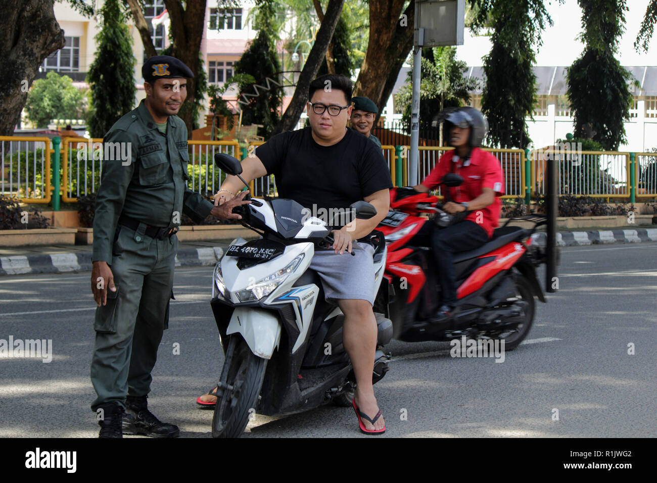 Lhokseumawe, Aceh, Indonesien. 13 Nov, 2018. Die islamische Scharia Polizeioffizier (Wilayatul Hisbah) gesehen stoppen ein Kraftfahrer einen Kurzschluß tragen während des routinemäßigen Razzien in Lhokseumawe. islamische Scharia Polizisten (Wilayatul Hisbah) bieten sarongs Für diejenigen, die die islamische Scharia durch Gewalt in der Stadt Lhokseumawe verletzt, Aceh ist die einzige Provinz in Indonesien mit der größten Bevölkerung von Muslimen in der Welt, der die islamische Scharia wie Ausschuss caning implementiert und die Durchführung von routinemäßigen Raids Für diejenigen, die Fest für Frauen und kurze Hosen für Männer gekleidet sind. (Credit Ima Stockfoto