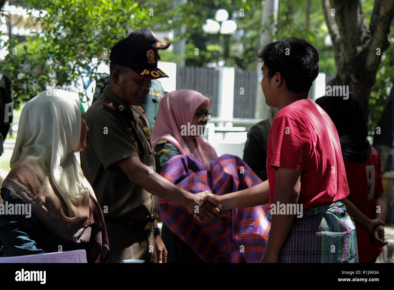 Lhokseumawe, Aceh, Indonesien. 13 Nov, 2018. Die islamische Scharia Polizeioffizier (Wilayatul Hisbah) gesehen Händeschütteln mit ein Mann mit einem Sarong während des routinemäßigen Razzien in der Stadt Lhokseumawe. islamische Scharia Polizisten (Wilayatul Hisbah) bieten sarongs Für diejenigen, die die islamische Scharia durch Gewalt in der Stadt Lhokseumawe verletzt, Aceh ist die einzige Provinz in Indonesien mit der größten Bevölkerung von Muslimen in der Welt, der die islamische Scharia wie Ausschuss caning implementiert und die Durchführung von routinemäßigen Raids Für diejenigen, die Fest für Frauen und kurze Hosen sind für mich angezogen Stockfoto