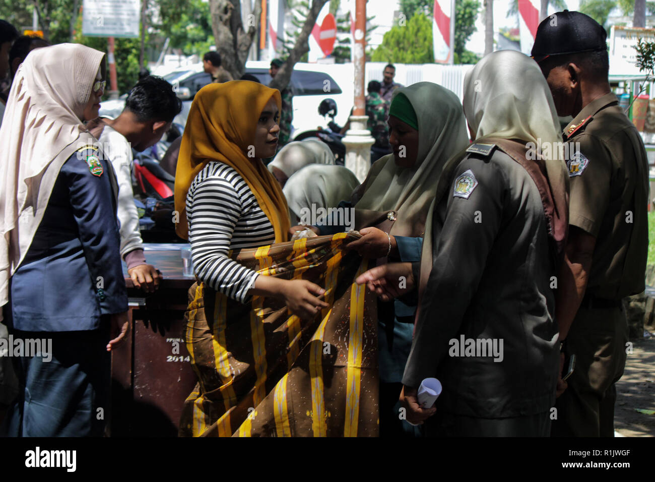 Lhokseumawe, Aceh, Indonesien. 13 Nov, 2018. Die islamische Scharia Polizeioffizier (Wilayatul Hisbah) gesehen ist das Binden einen Sarong mit einer Frau, die die islamische Scharia durch Gewalt in der Stadt Lhokseumawe. islamische Scharia Polizisten (Wilayatul Hisbah) verletzt bieten sarongs Für diejenigen, die die islamische Scharia durch Gewalt in der Stadt Lhokseumawe verletzt, Aceh ist die einzige Provinz in Indonesien mit der größten Bevölkerung von Muslimen in der Welt, der die islamische Scharia wie Ausschuss caning implementiert und die Durchführung von routinemäßigen Raids Für diejenigen, die Fest für Frauen und kurze Hosen angezogen sind Stockfoto