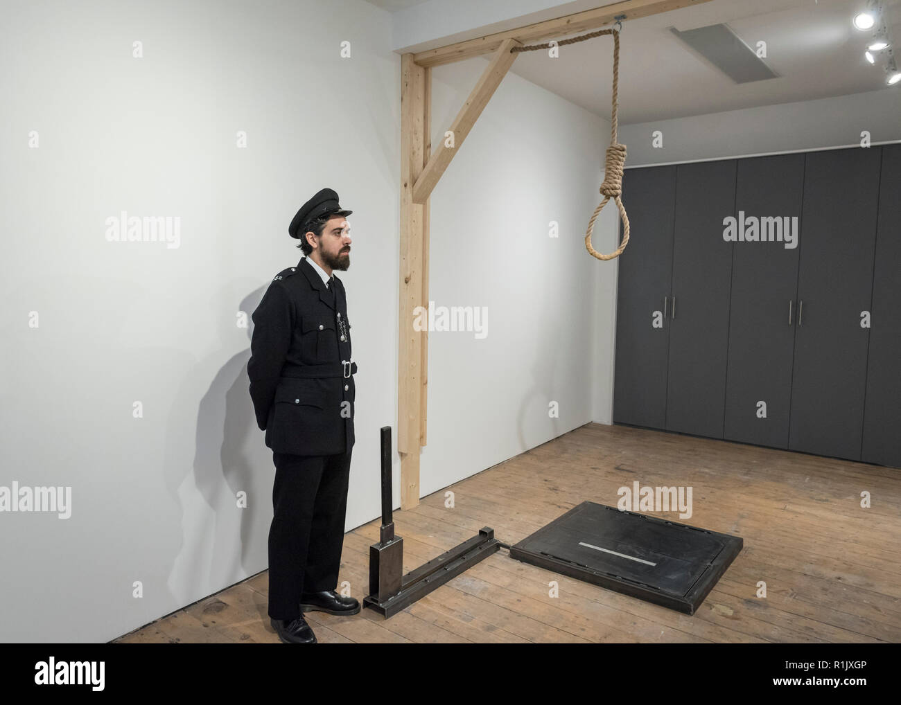 London, Großbritannien. 13. November 2018. Ein Mitarbeiter, als Gefängniswärter posiert, Ansichten eines Galgenraten Schlinge. Vorschau von "Froh, dass ich es Es ist, eine neue Arbeit von der irischen Künstlerin Christina Reihill in Bermondsey Project Space. Die interaktiven Kunstwerk betrachtet das Leben und den Tod von Ruth Ellis, die letzte Frau in Großbritannien gehängt werden, nachdem sie ihren Liebhaber erschossen, Rennfahrer, David Blakely 1955. Auf dem Display sind Interpretation des Künstlers von Ruth Ellis' Gefängniszelle, einschließlich Möbel und Requisiten, die hängenden Zimmer zusammen mit einem Video anzeige der Künstler im Gespräch. Credit: Stephen Chung/Alamy leben Nachrichten Stockfoto