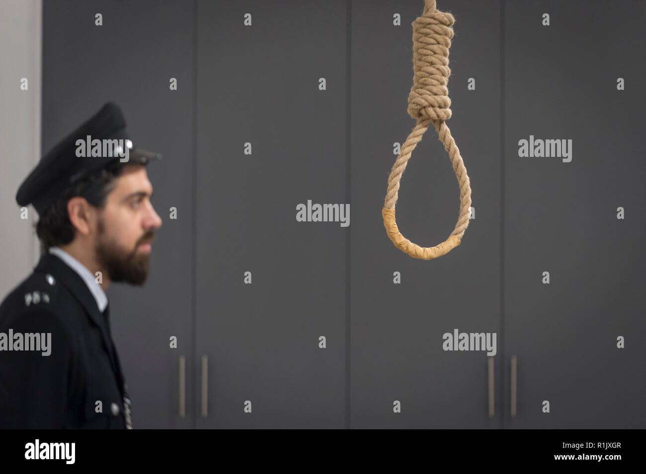 London, Großbritannien. 13. November 2018. Ein Mitarbeiter, als Gefängniswärter posiert, Ansichten eines Galgenraten Schlinge. Vorschau von "Froh, dass ich es Es ist, eine neue Arbeit von der irischen Künstlerin Christina Reihill in Bermondsey Project Space. Die interaktiven Kunstwerk betrachtet das Leben und den Tod von Ruth Ellis, die letzte Frau in Großbritannien gehängt werden, nachdem sie ihren Liebhaber erschossen, Rennfahrer, David Blakely 1955. Auf dem Display sind Interpretation des Künstlers von Ruth Ellis' Gefängniszelle, einschließlich Möbel und Requisiten, die hängenden Zimmer zusammen mit einem Video anzeige der Künstler im Gespräch. Credit: Stephen Chung/Alamy leben Nachrichten Stockfoto