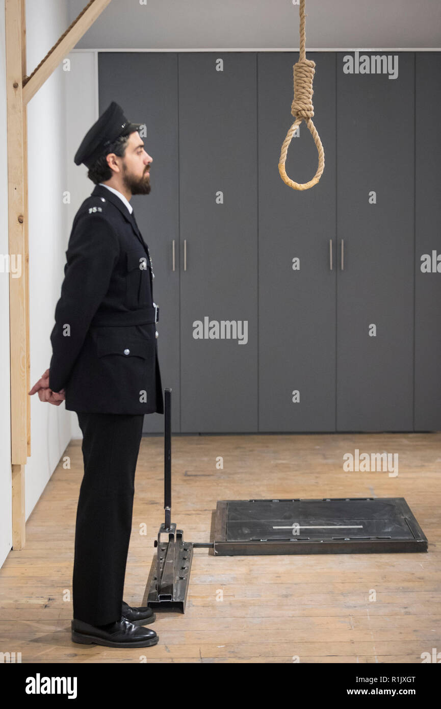 London, Großbritannien. 13. November 2018. Ein Mitarbeiter, als Gefängniswärter posiert, Ansichten eines Galgenraten Schlinge. Vorschau von "Froh, dass ich es Es ist, eine neue Arbeit von der irischen Künstlerin Christina Reihill in Bermondsey Project Space. Die interaktiven Kunstwerk betrachtet das Leben und den Tod von Ruth Ellis, die letzte Frau in Großbritannien gehängt werden, nachdem sie ihren Liebhaber erschossen, Rennfahrer, David Blakely 1955. Auf dem Display sind Interpretation des Künstlers von Ruth Ellis' Gefängniszelle, einschließlich Möbel und Requisiten, die hängenden Zimmer zusammen mit einem Video anzeige der Künstler im Gespräch. Credit: Stephen Chung/Alamy leben Nachrichten Stockfoto
