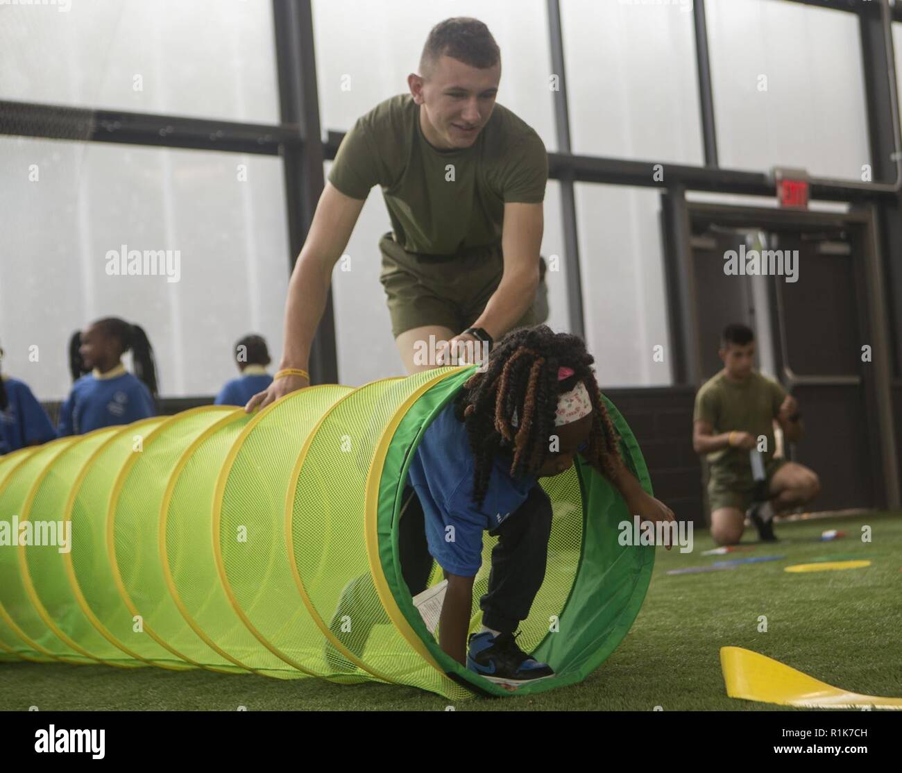 Ein US-Marine mit 2Nd Marine Division interagiert mit einer Studentin aus Thomas Johnson Grundschule während eines Jugendbereich tag Ereignis als Teil der Flotte Woche Baltimore Baltimore, Md.; Okt. 8; 2018. Flotte Woche Baltimore können Anwohner Zeugnis aus erster Hand die maritimen Fähigkeiten der US Navy und Marine Corps, während auch die Förderung kommunaler Wachstum durch Community Relations Projekte. Stockfoto