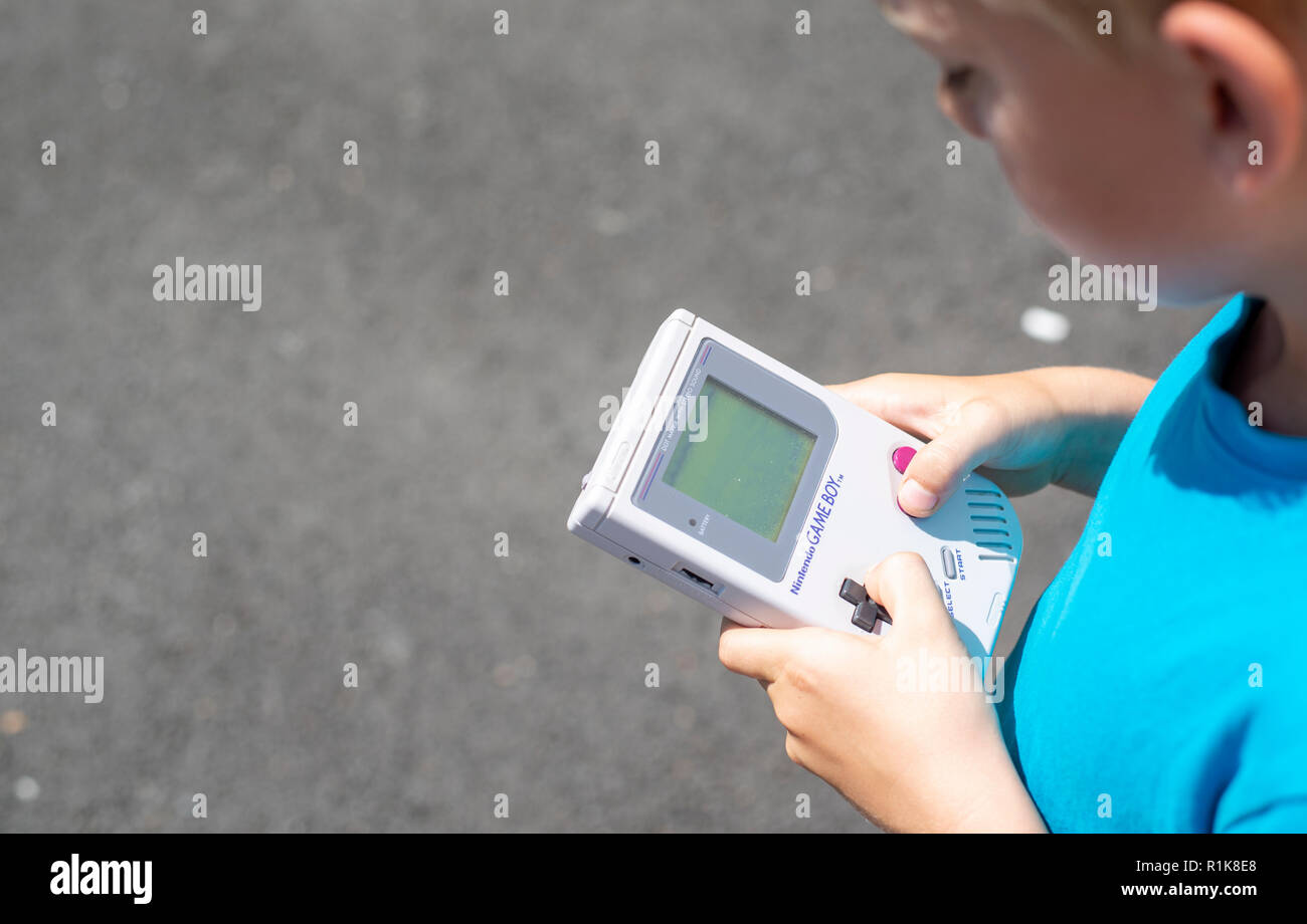 Junge mit seinem Nintendo Gameboy Computerspiele zu spielen. 90er Jahre Ambiente. Im Freien einstellen. Stockfoto