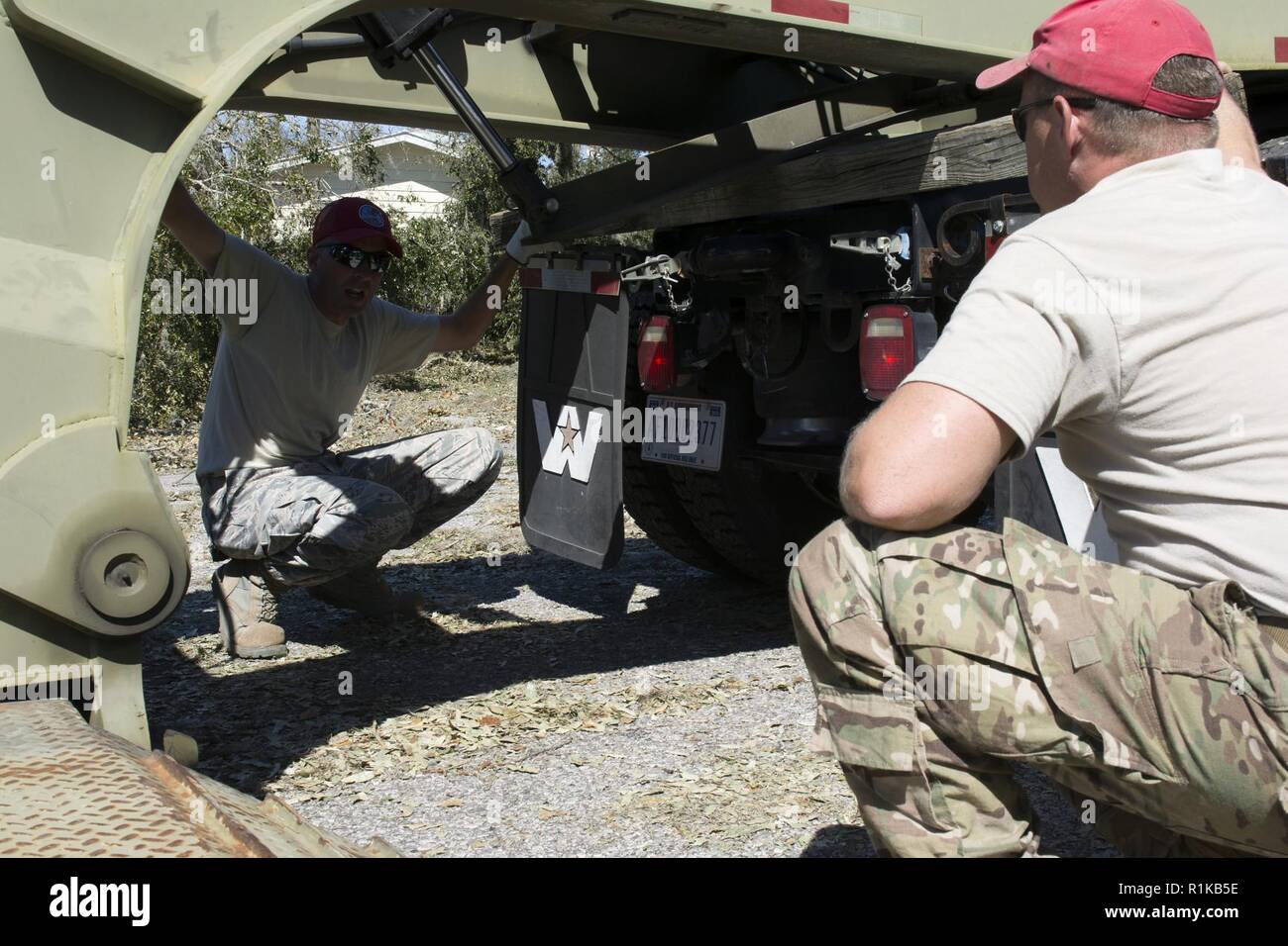 Master Sgt. Christopher Fischer und Staff Sgt. Blake Gibson, schwere Ausrüstung Operatoren aus der 202. Geben Sie der Camp Blanding, Fla., koordinieren das Abladen des Kompaktladers aus einem lowboy Trailer in der Wohngegend von Deerpoint See, Fla., Okt. 12, 2018 lenken. Der Kompaktlader ist ein wertvolles Werkzeug für den Ausbau Schneebruch und Rückstände von Straßen, die für Rettungsdienste nutzbar. Hurricane Michael stark beeinträchtigt das Panama City, Zerstörung hinterlassen in ihm ist. Stockfoto