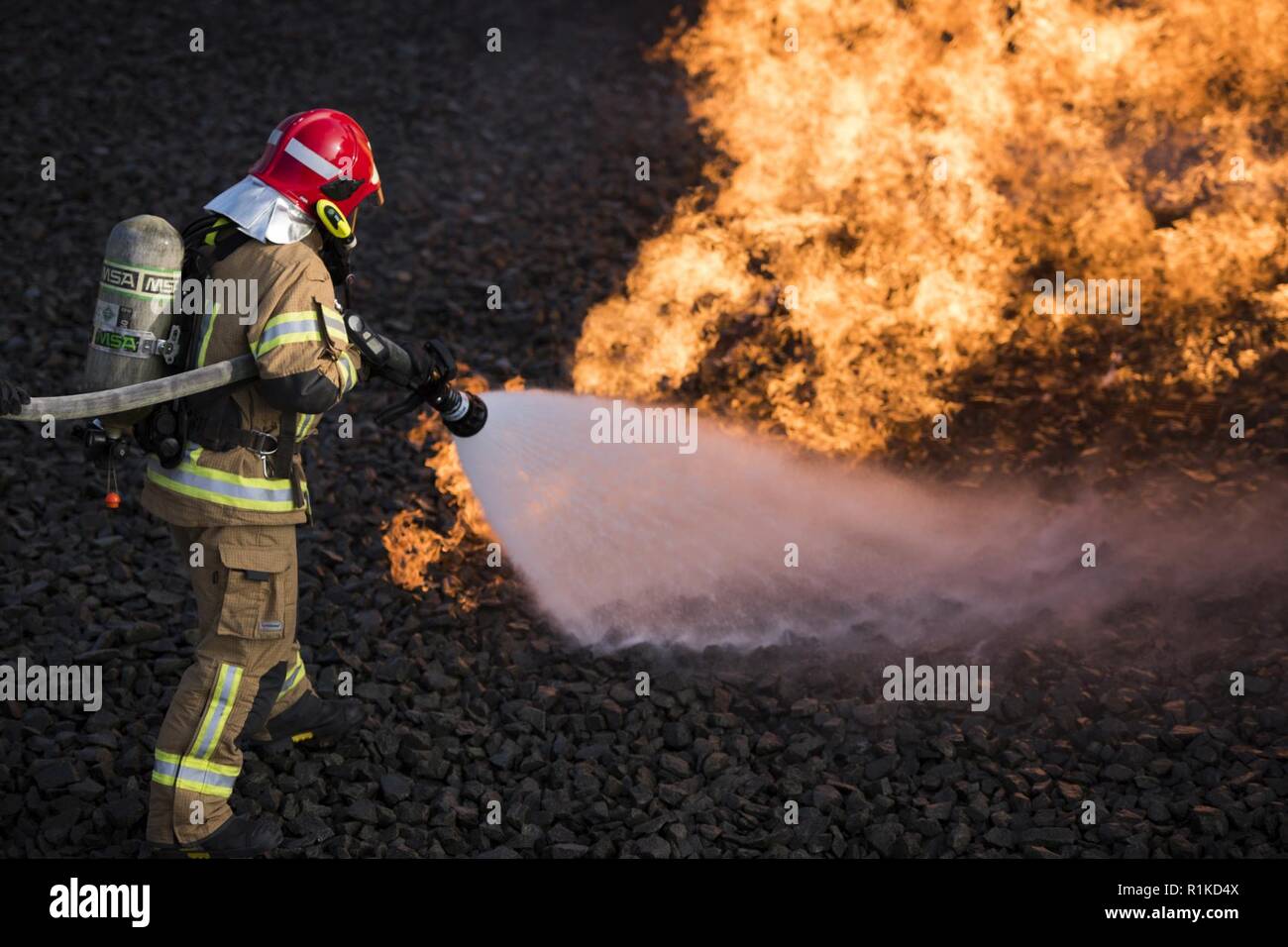 Eine lettische Luftwaffe Feuerwehrmann löscht einen simulierten Brand während einer US Luft Kräfte in Europa, die NATO Feuerwehrmann Partnerschaft Kurs auf der Air Base Ramstein, Deutschland, Okt. 10, 2018. Der Kurs aktiviert NATO-Verbündeten zusammen mit NATO-crash und Brand Verfahren in einer simulierten Umgebung zu trainieren. Stockfoto