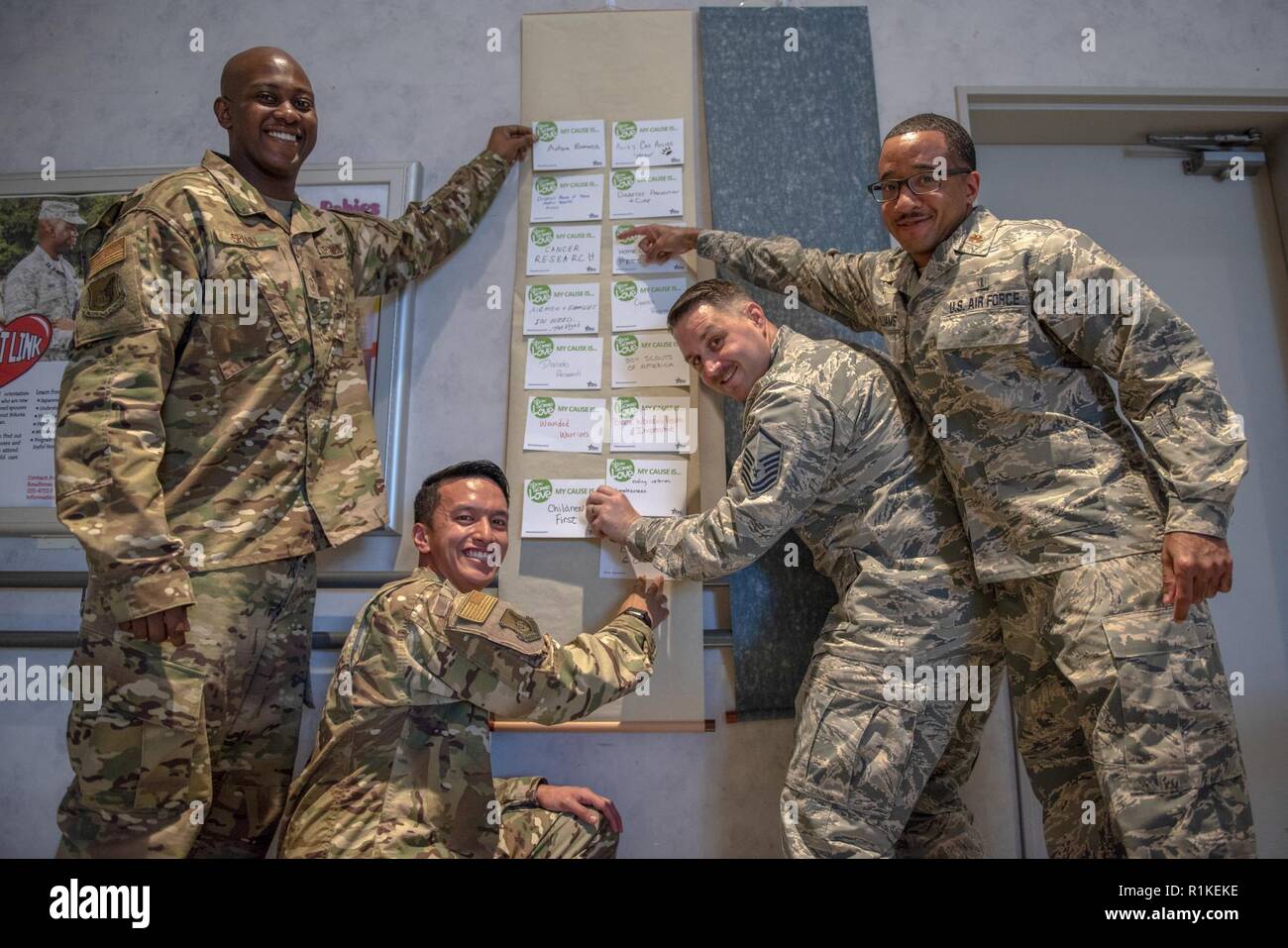 Flieger vom 374. Airlift Wing posieren für ein Foto mit ihren Ursachen der Wahl an der Kombinierten Bundestagswahlkampf Kick-off-Veranstaltung in Yokota Air Base, Japan, 15. Oktober 2018. Die Kampagne bietet allen Mitarbeitern die Möglichkeit, die Lebensqualität für alle durch Spenden zu verbessern, um eine Vielzahl von Ursachen. Stockfoto