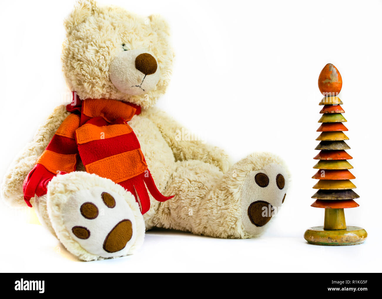 Flauschige Teddybär mit roter Schal und Holz- ring Stapler auf weißem Hintergrund. Alte vintage Spielzeug. Stockfoto