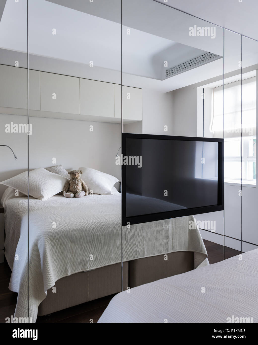 Flachbildschirm Fernsehen auf verspiegelte Wand im Schlafzimmer Stockfoto