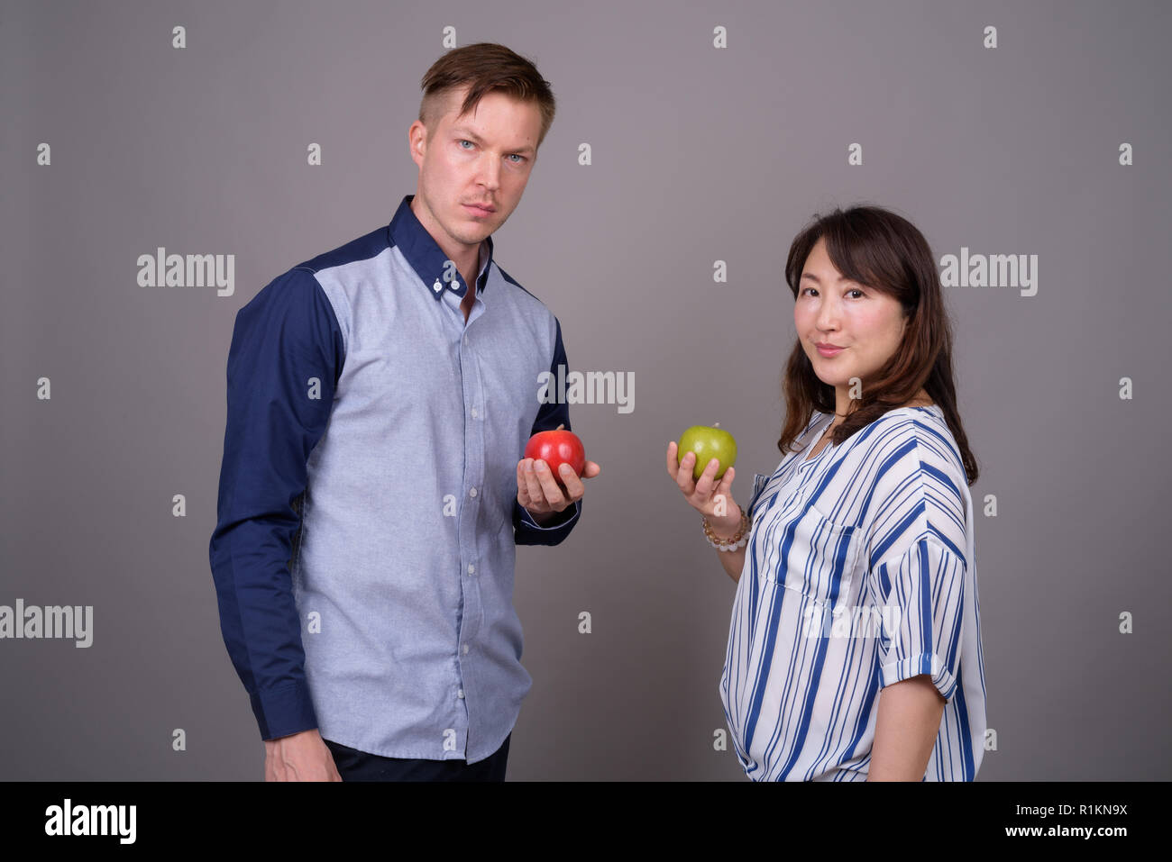 Multi-ethnische Vielfalt Paar im Studio mit grünen und roten Apfel Obst Stockfoto