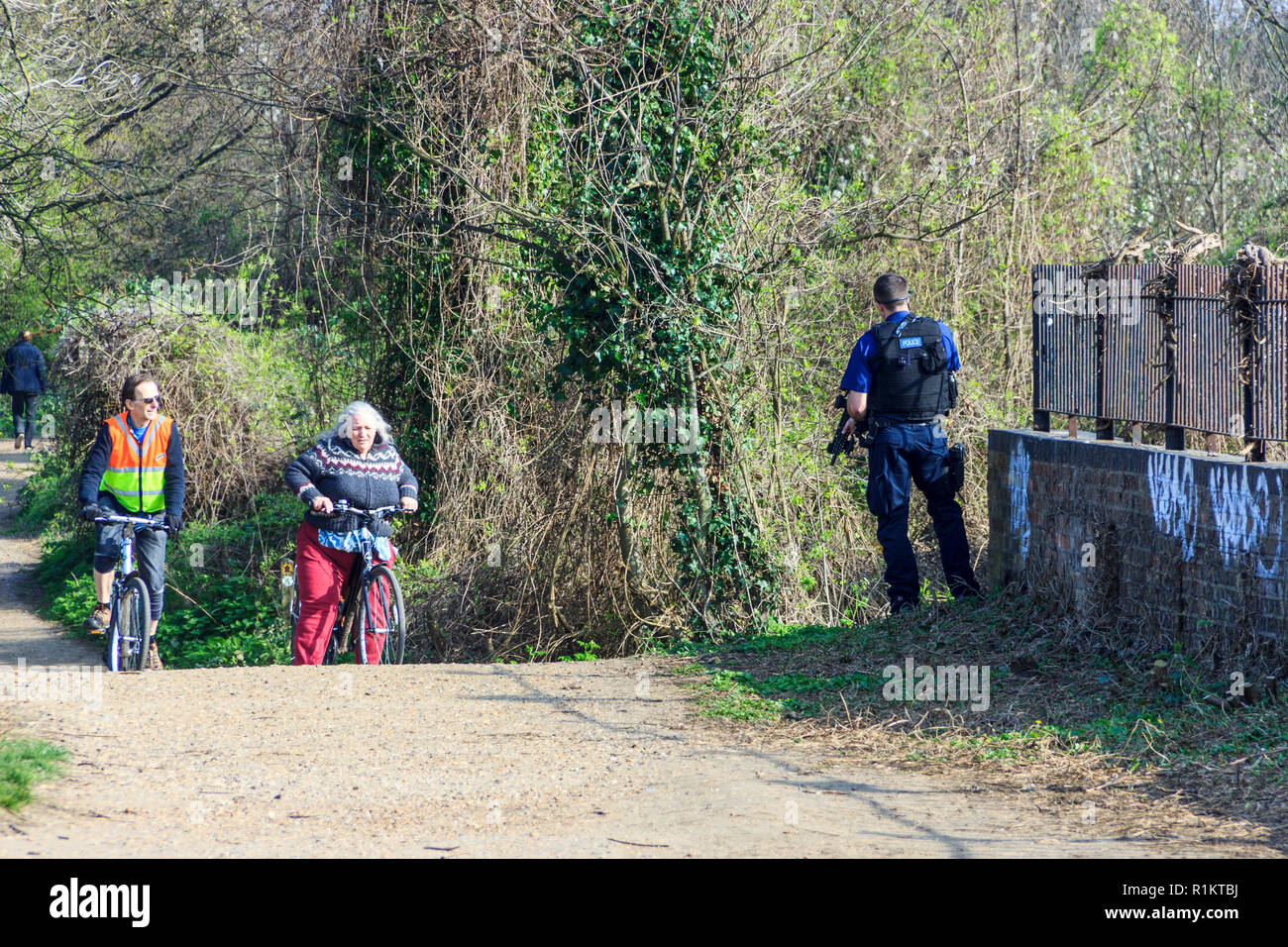 Eine bewaffnete Polizisten überraschungen Radfahrer auf Park entfernt, einem öffentlichen Nature Trail im Norden von London, UK, auf einem Frühling Nachmittag Stockfoto