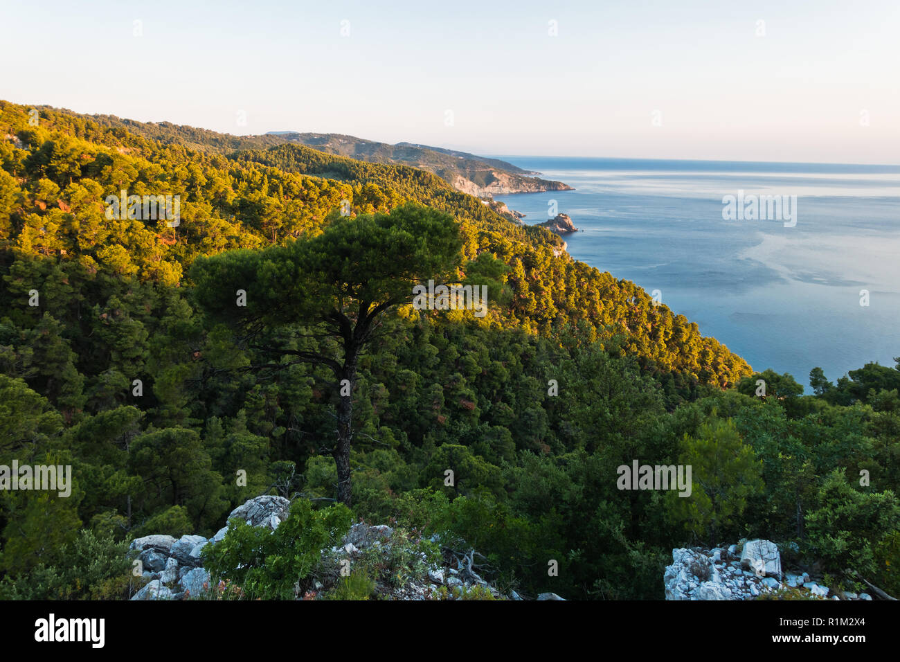 Sicht von Insel Hinterstraße in die felsige Küste mit Agios Ioanis Kirche bei Sonnenaufgang, Insel Skopelos, Griechenland Stockfoto