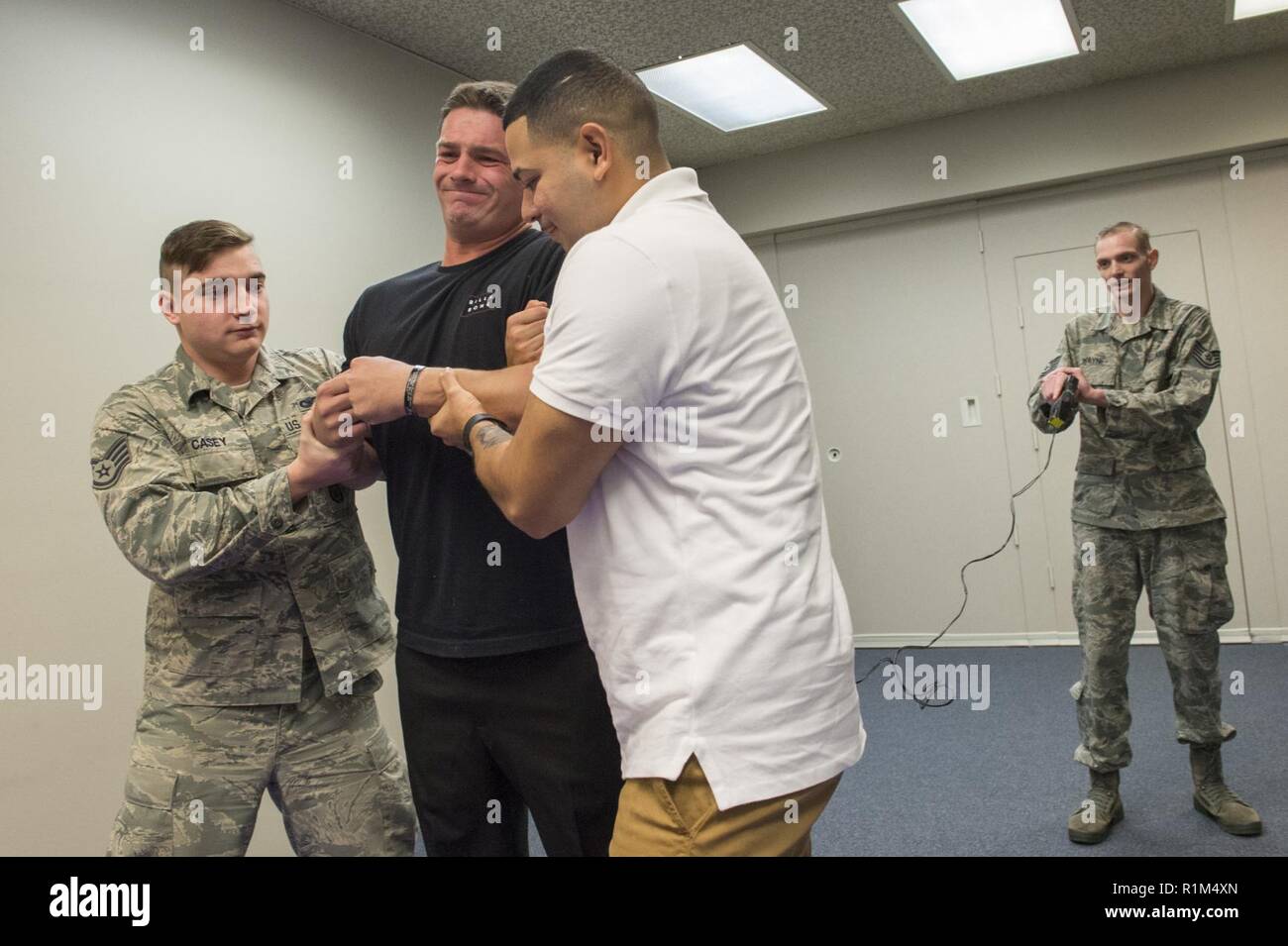 Josh Eldridge, zweite links, ein Polizeioffizier mit der 673 d Security Forces Squadron, während Taser Einarbeitung Ausbildung bei Joint Base, Alaska, Okt. 18, 2018 schockiert. Elektroschocker bieten JBER Verteidiger mit einem nicht-tödliche Waffe, die sich unterwerfen kann fliehen, kämpferische, oder potenziell gefährliche Menschen, die sonst zu mehr tödlichen Waffen wie Feuerwaffen unterzogen worden. Eldridge, ein Eingeborener von Anchorage, Alaska, und eine Marine Corps Veteran, die sich freiwillig für die Demonstration schockiert zu sein. Stockfoto