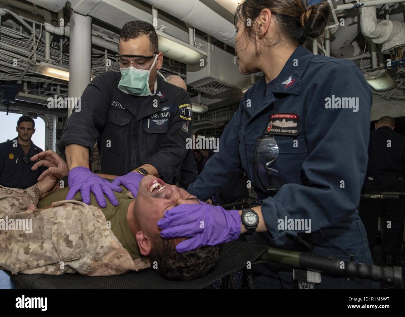 ARABIAN GULF (Okt. 2010) 11, 2018) Hospital Corpsmen 2. Klasse Israel Castro und Alyssa Gupiteo untersuchen simulierten Verletzungen des Marine Corps Sgt. Markieren Mendez, an die 13 Marine Expeditionary Unit (MEU), während einer Messe Unfallversicherung bohren an Bord der Wasp-Klasse amphibisches Schiff USS Essex (LHD2) während der regelmäßigen Bereitstellung mit der Essex Amphibious Ready Group (ARG) und 13 MEU. Essex ist eine tödliche, flexibel, und anhaltende Navy-Marine Corps Team in die USA 5 Flotte Bereich der Maßnahme zur Unterstützung der Marine im Einsatz für die Stabilität und Sicherheit in der Zentrale zu gewährleisten Stockfoto