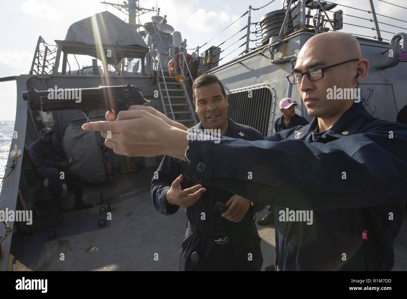 Mittelmeer (Okt. 2010) 17, 2018) Lt.Cmdr. Stan Chen, rechts, erhält Training auf dem M9 Pistole von Gunner Mate 1. Klasse Jose Sanchez während einer kleinen Arme Qualifikation Kurs an Bord der Arleigh-Burke-Klasse geführte Anti-raketen-Zerstörer USS Arleigh Burke (DDG51) im Mittelmeer 17. Okt. 2018. Arleigh Burke, homeported in der Naval Station Norfolk, ist die Durchführung von naval Operations in den USA 6 Flotte Bereich der Maßnahmen zur Unterstützung der US-amerikanischen nationalen Sicherheitsinteressen in Europa und Afrika. Stockfoto