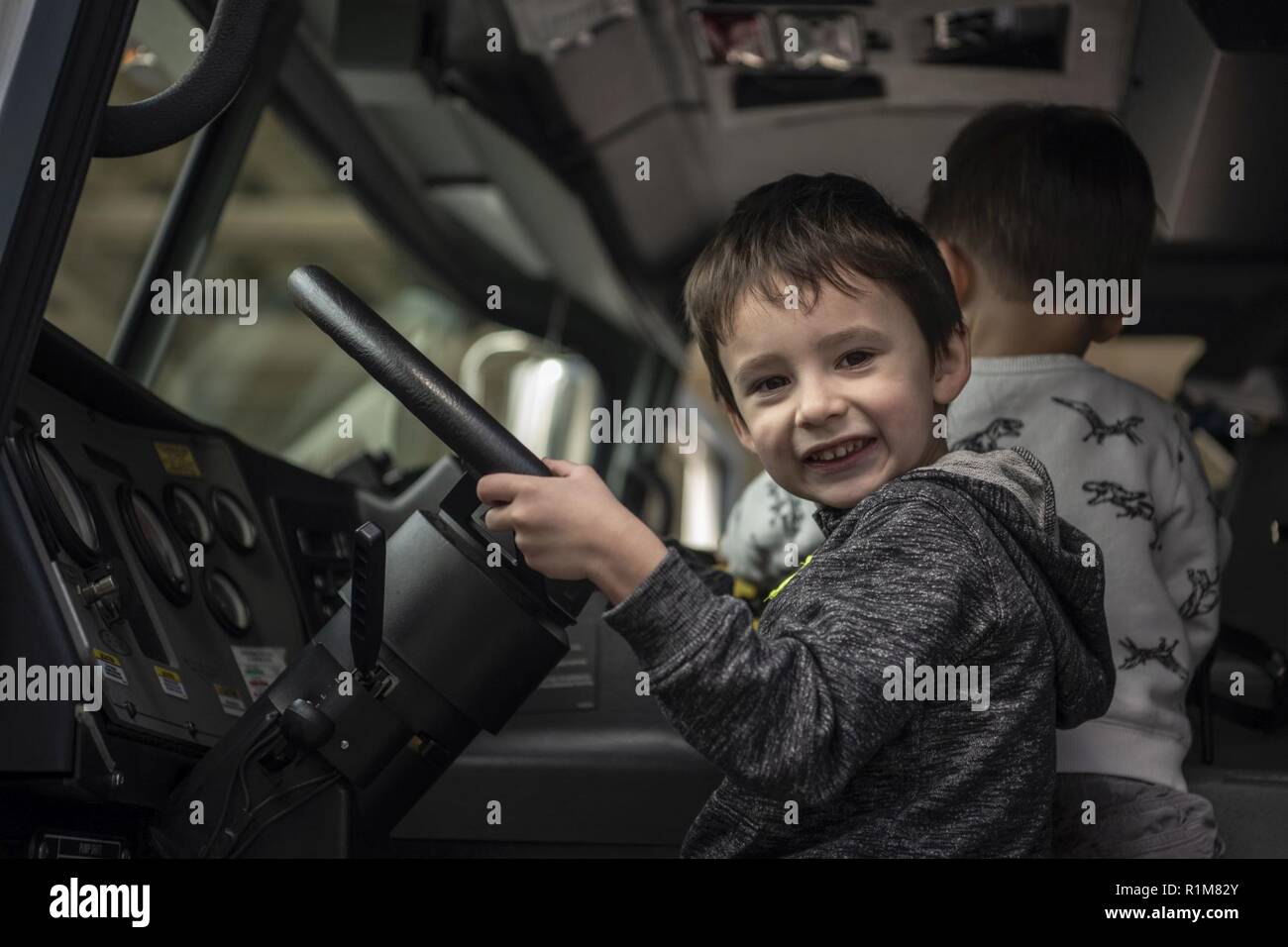Ein Zuschauer Pausen für ein Foto in einem 35Th Bauingenieur Squadron firetruck bei Tag, in der Nähe von Misawa Air Base, Japan, Okt. 12, 2018. Die 35. CES präsentiert Stände für die Feuerwehr und die Beseitigung von Explosivstoffen Team. Gäste können die Tour Feuer Lkw und sehen Sie Demonstrationen auf Löschanlagen. EOD auch gezeigt, die Verwendung von Geräten verwendet nicht explodierter Verordnungen zu löschen. Stockfoto
