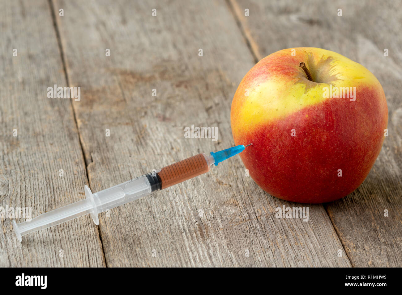 Spritze und Apple. Konzept für genetisch veränderte Lebensmittel und kosmetische Medizin Stockfoto