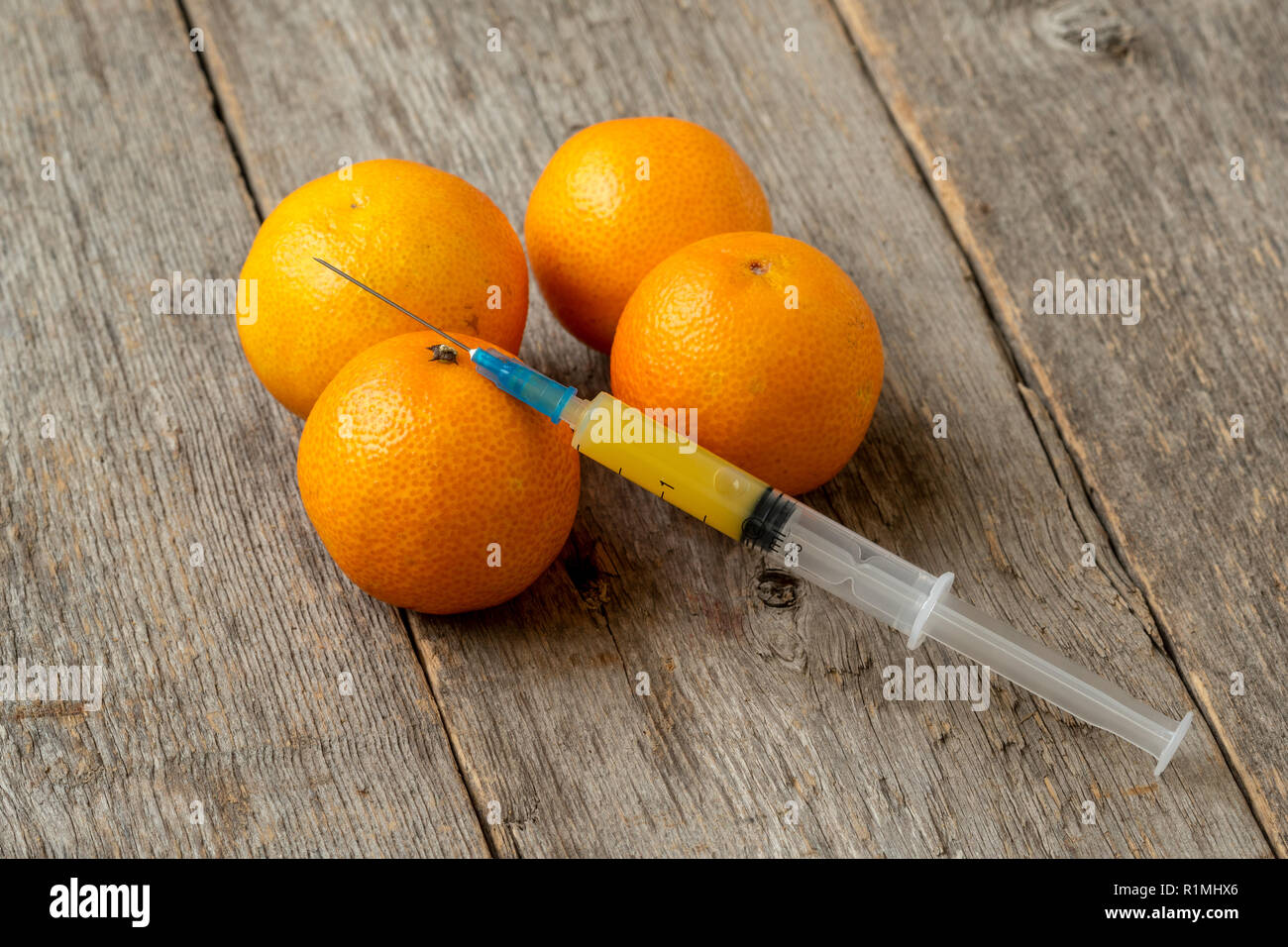Spritze und Mandarinen. Konzept für genetisch veränderte Lebensmittel und kosmetische Medizin Stockfoto